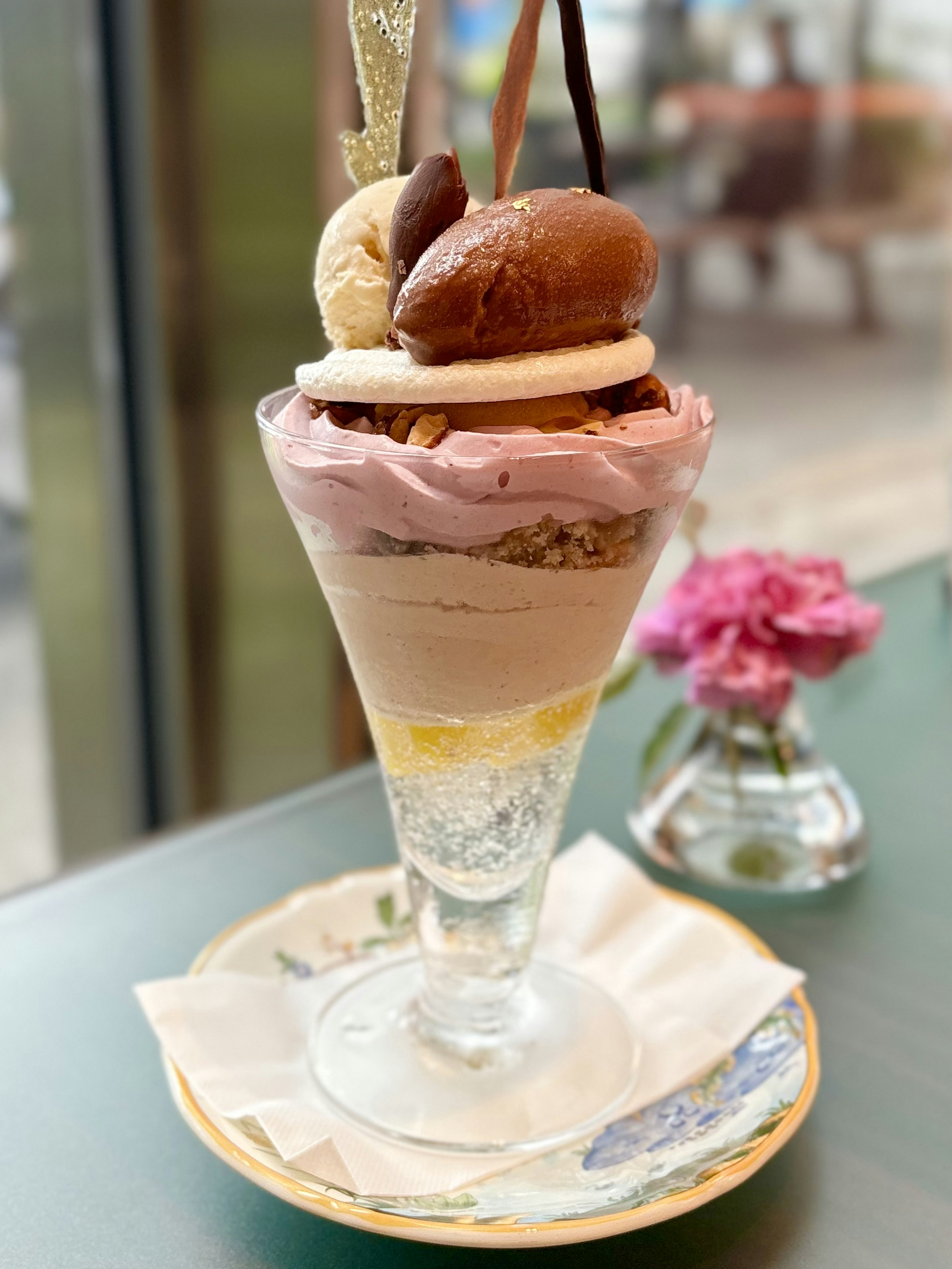 Parfait de glace coloré servi dans un verre transparent avec plusieurs saveurs et une petite décoration florale