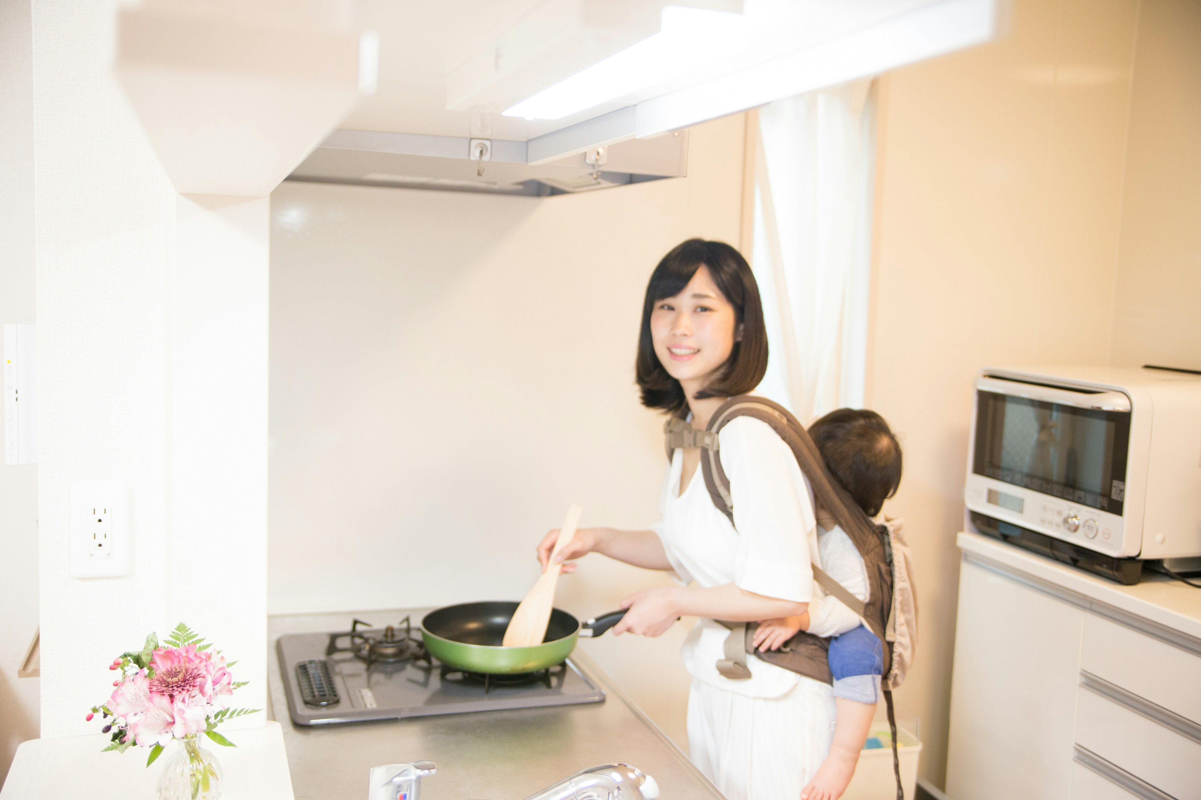 Mujer cocinando en una cocina con un niño en la espalda