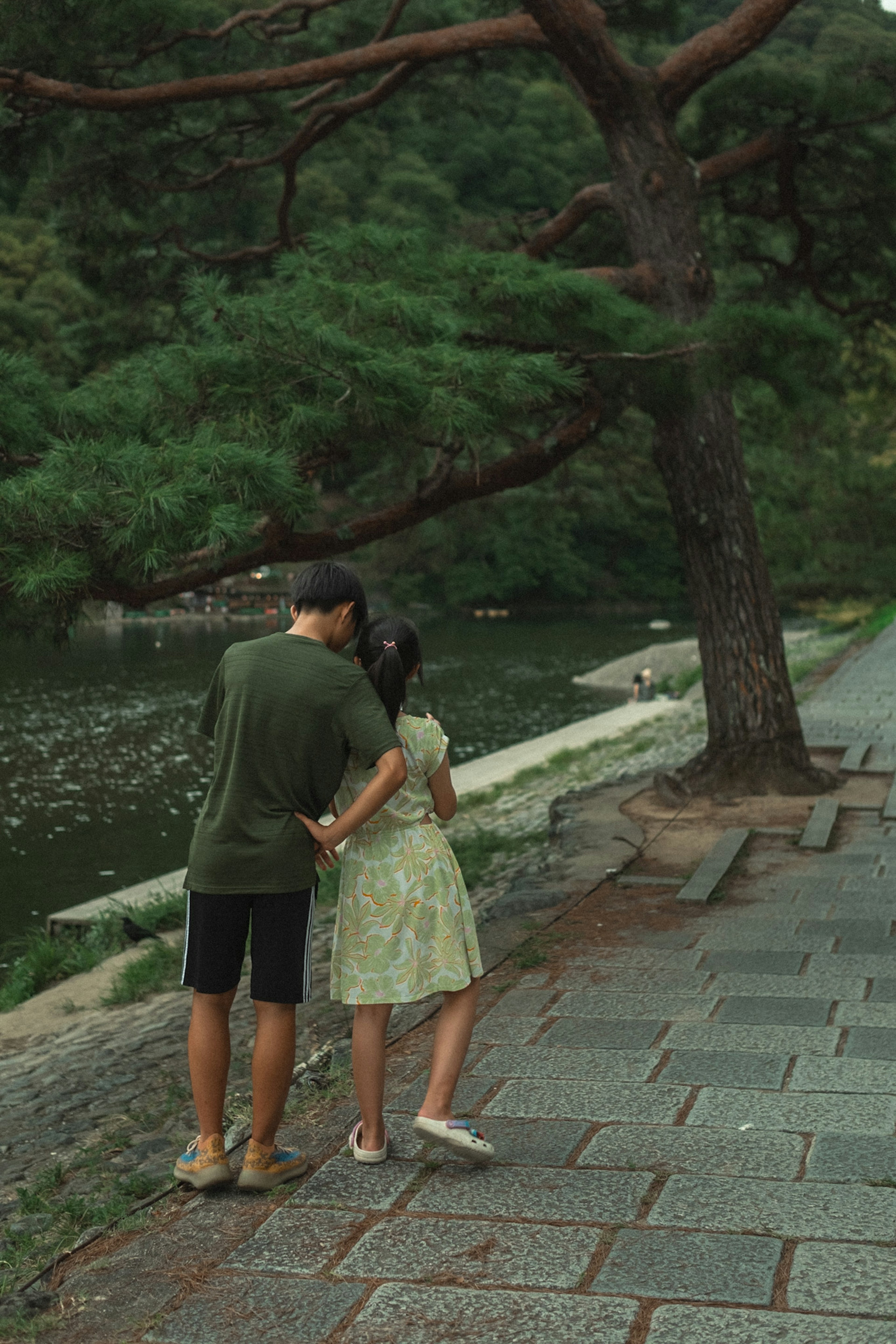 緑の公園で寄り添うカップル　水辺の風景　カジュアルな服装