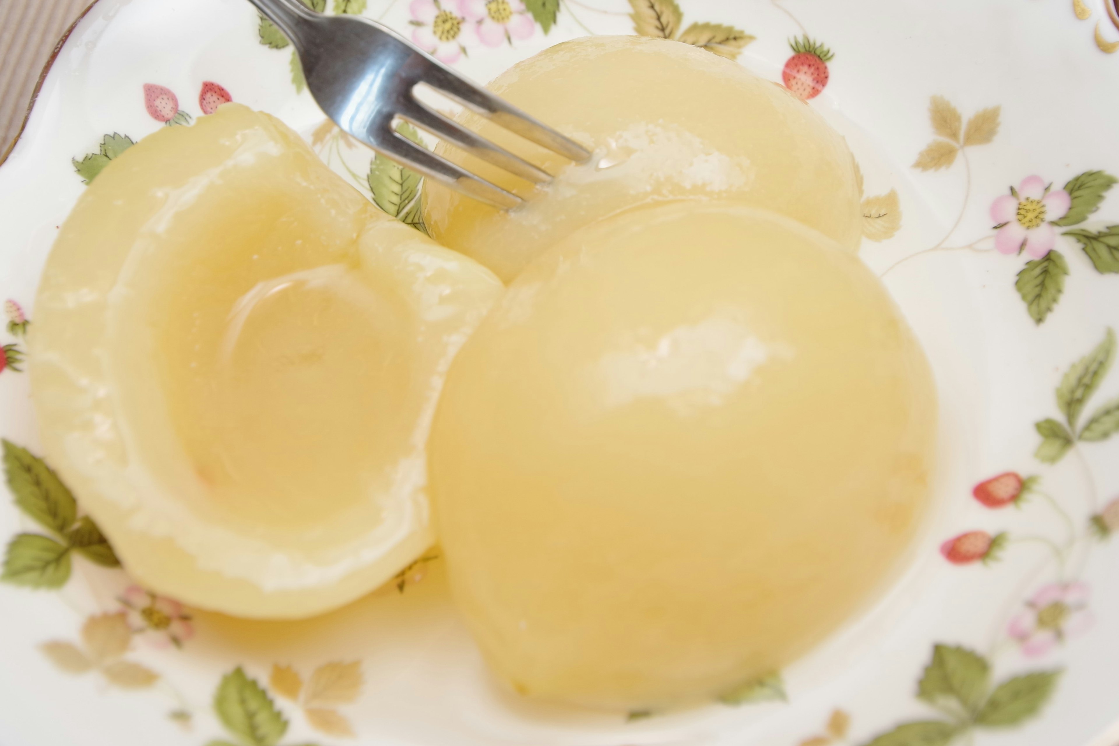 Canned fruit on a floral plate with a fork inserted