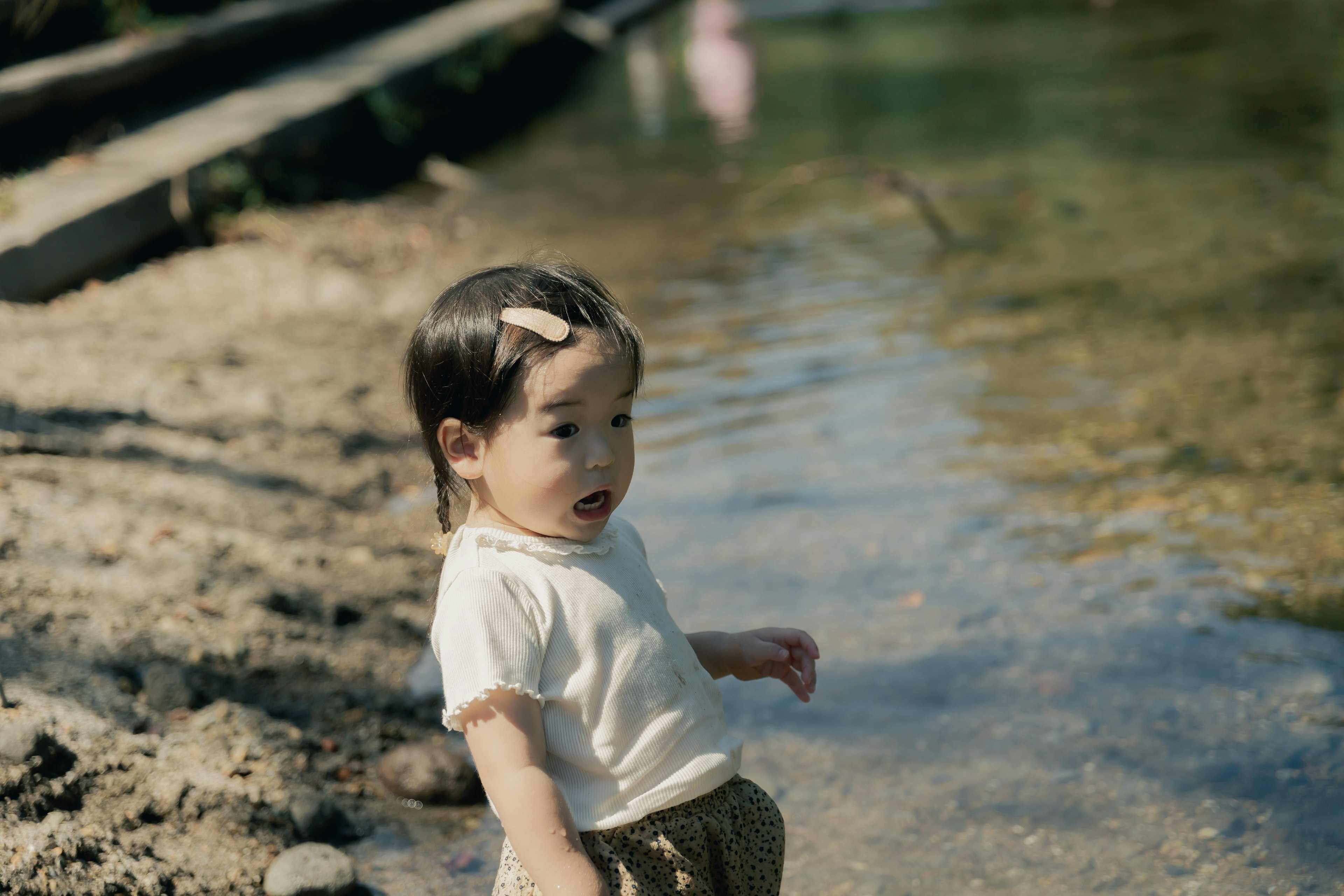 Une jeune fille debout au bord de l'eau entourée par la nature