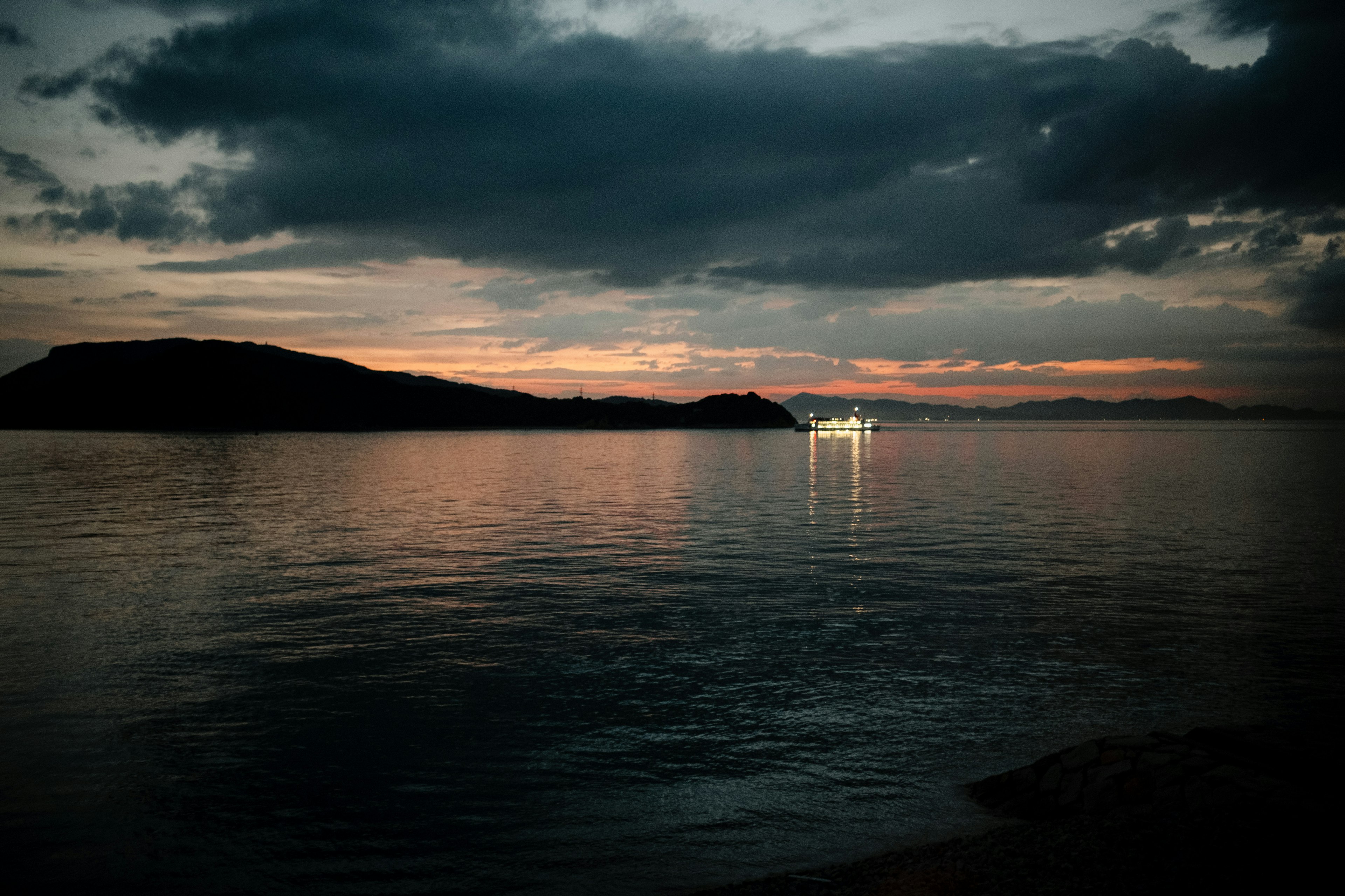 Lac calme reflétant la lumière du coucher de soleil et des nuages sombres