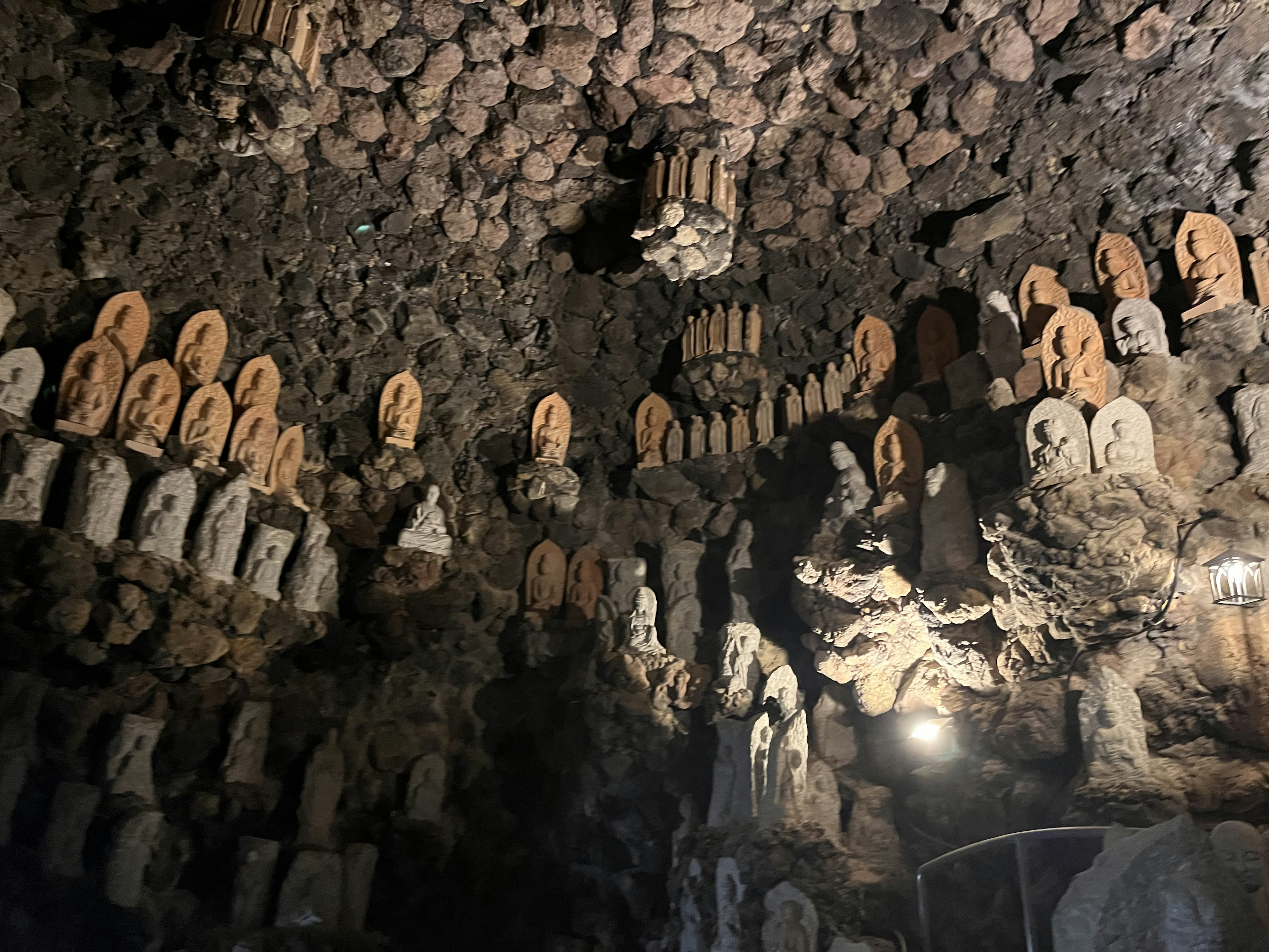 A mystical cave interior filled with numerous Buddha statues and stone carvings