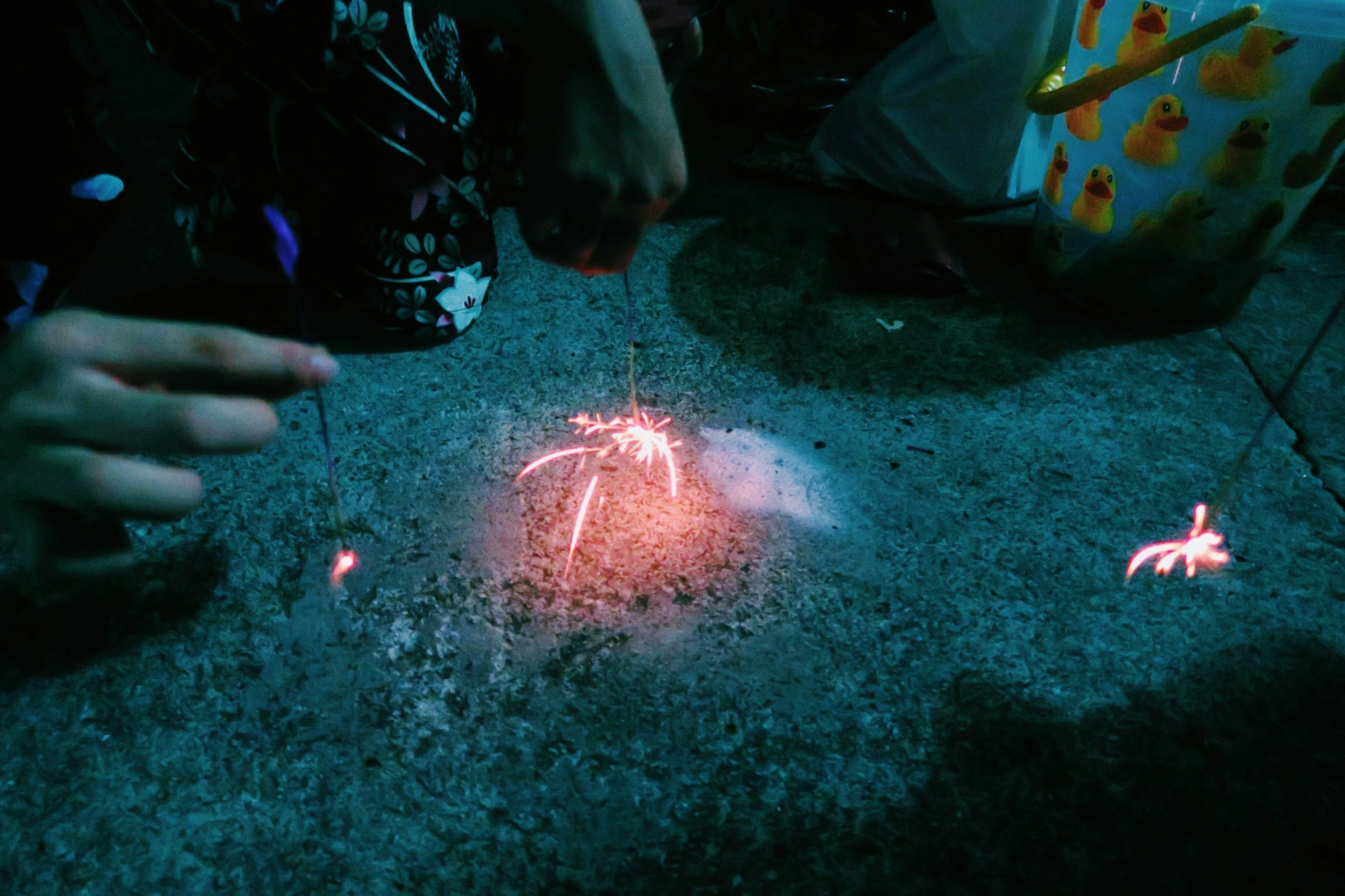 Mano de niño encendiendo fuegos artificiales en una superficie oscura