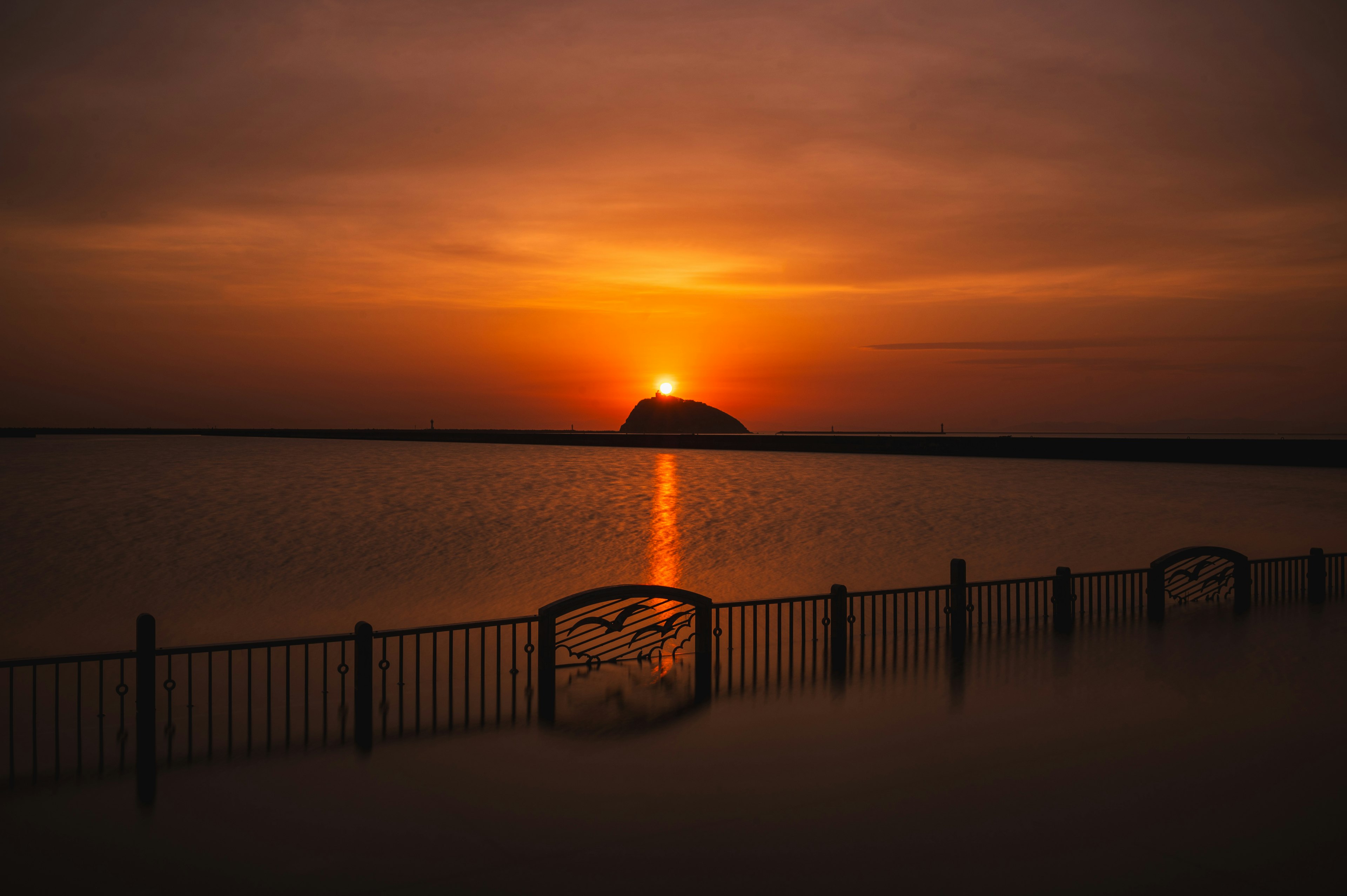 夕日が水面に反射する風景とフェンス