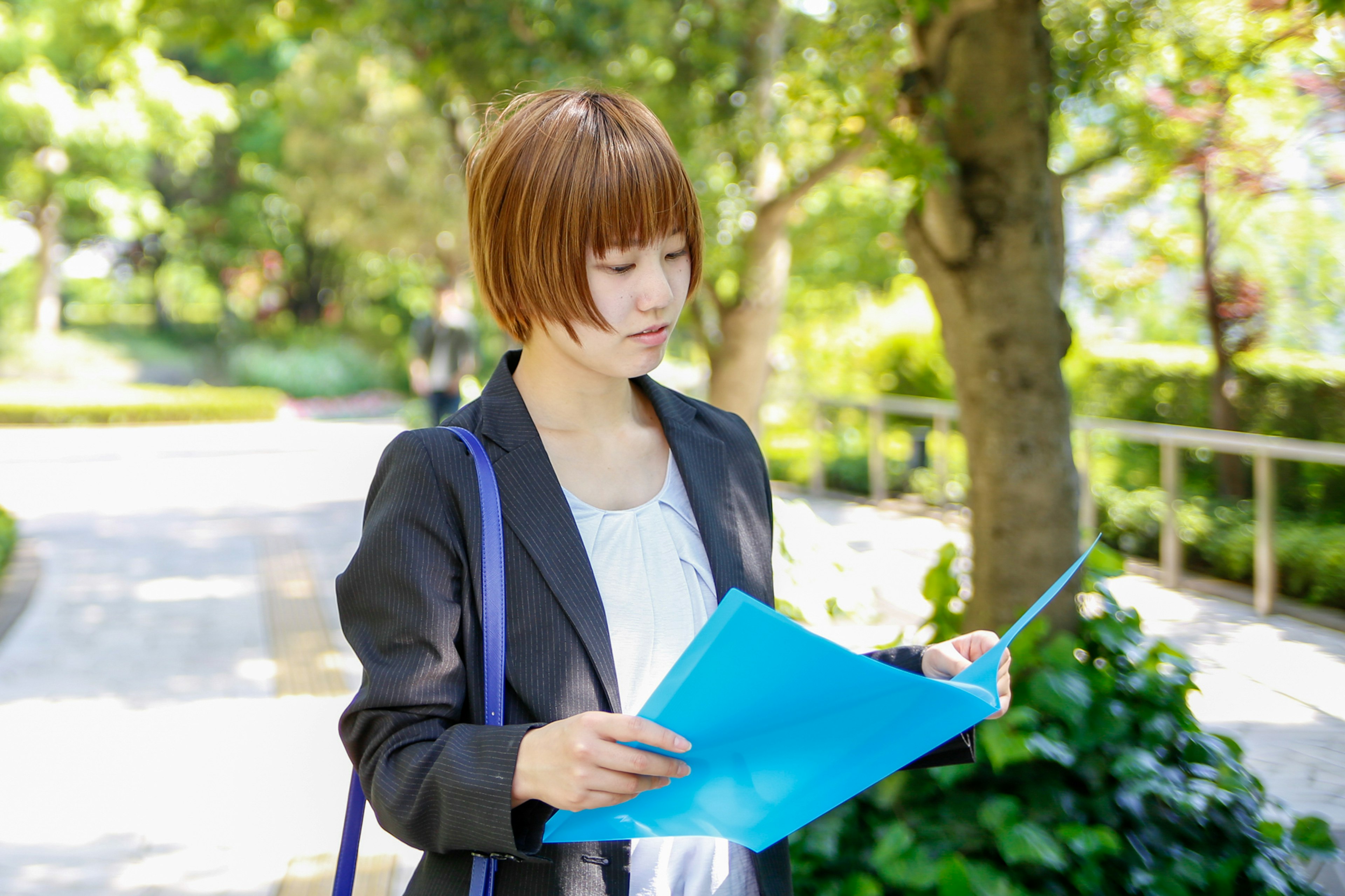 Femme en tenue professionnelle tenant des documents dans un parc