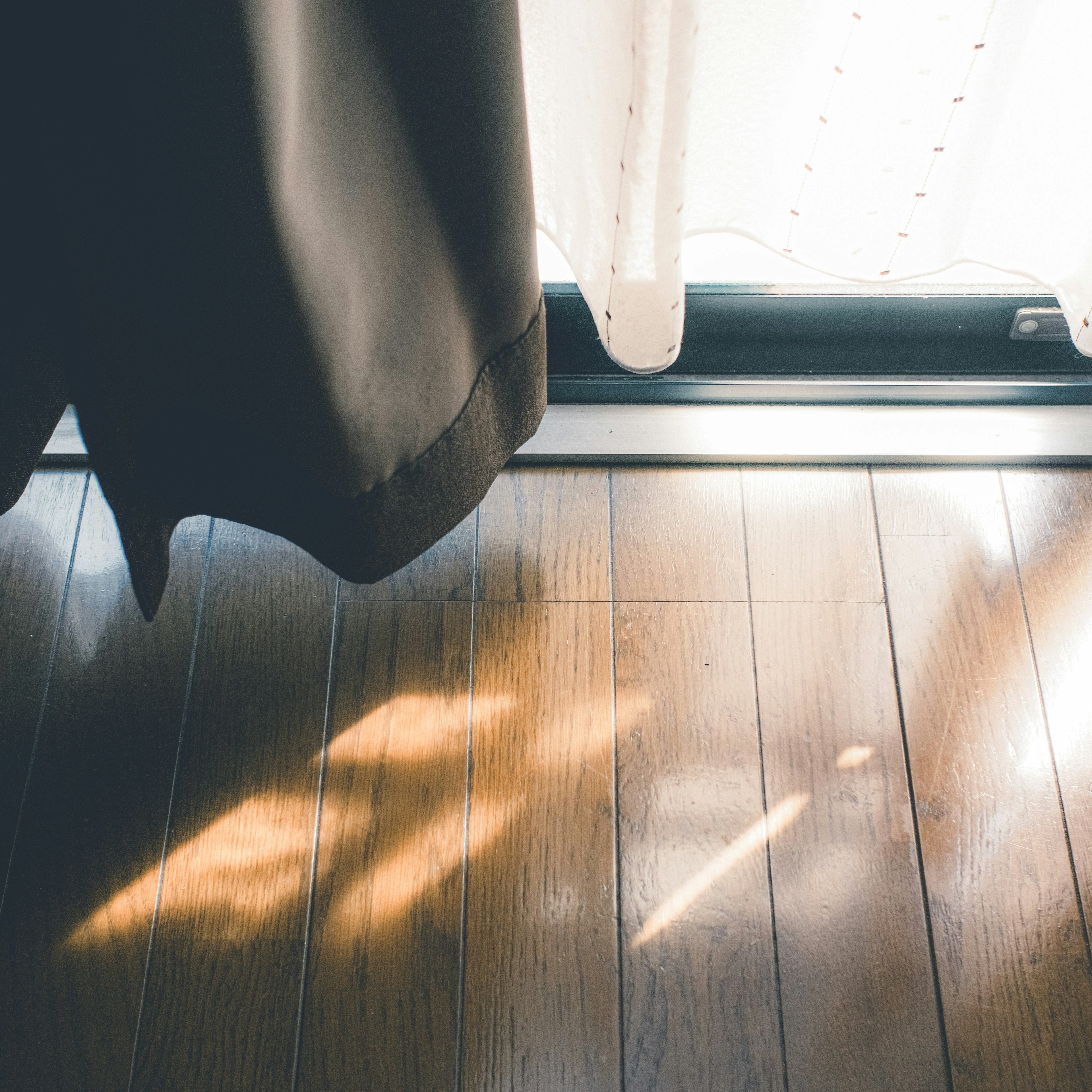 View of a window with part of a curtain and wooden floor