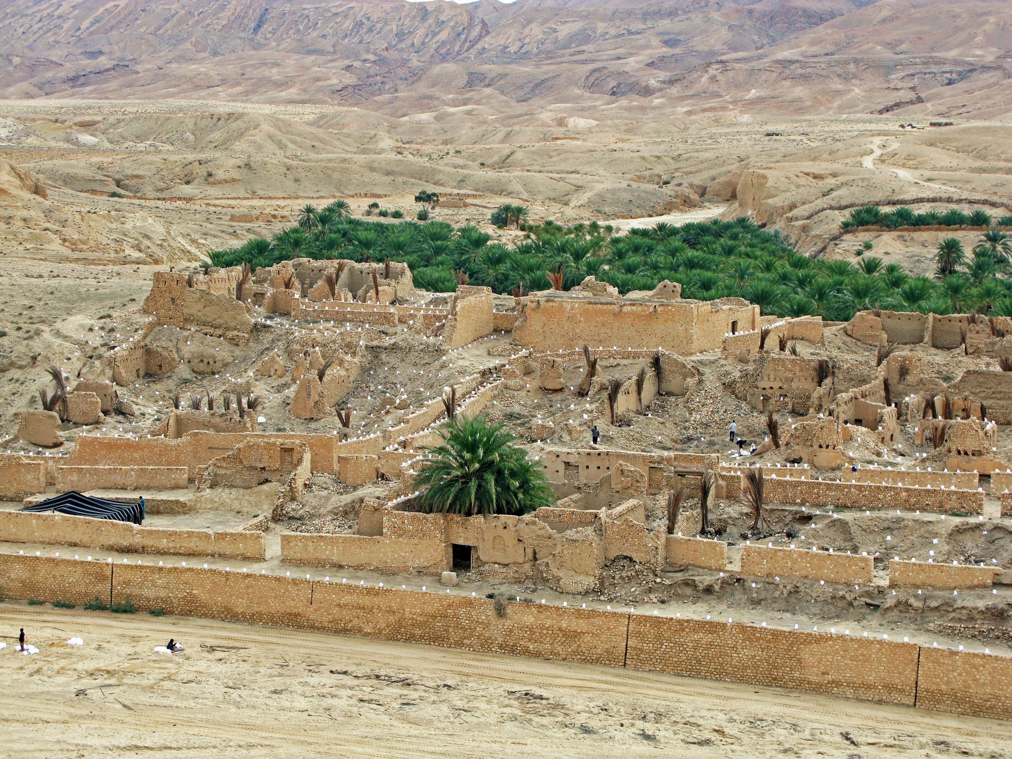 Ancient ruins surrounded by desert landscape with scattered green trees