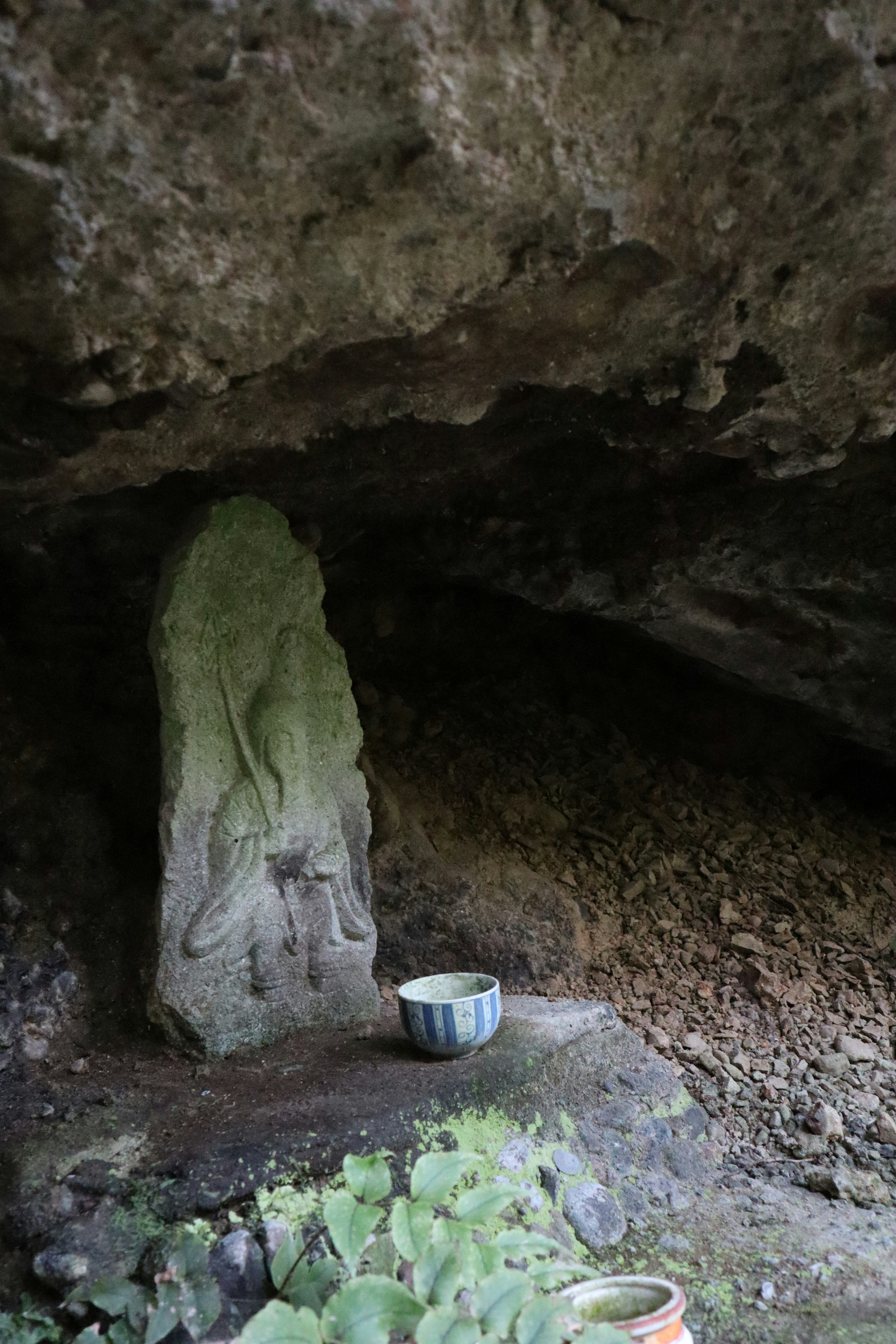 Scultura antica sotto una roccia con una ciotola