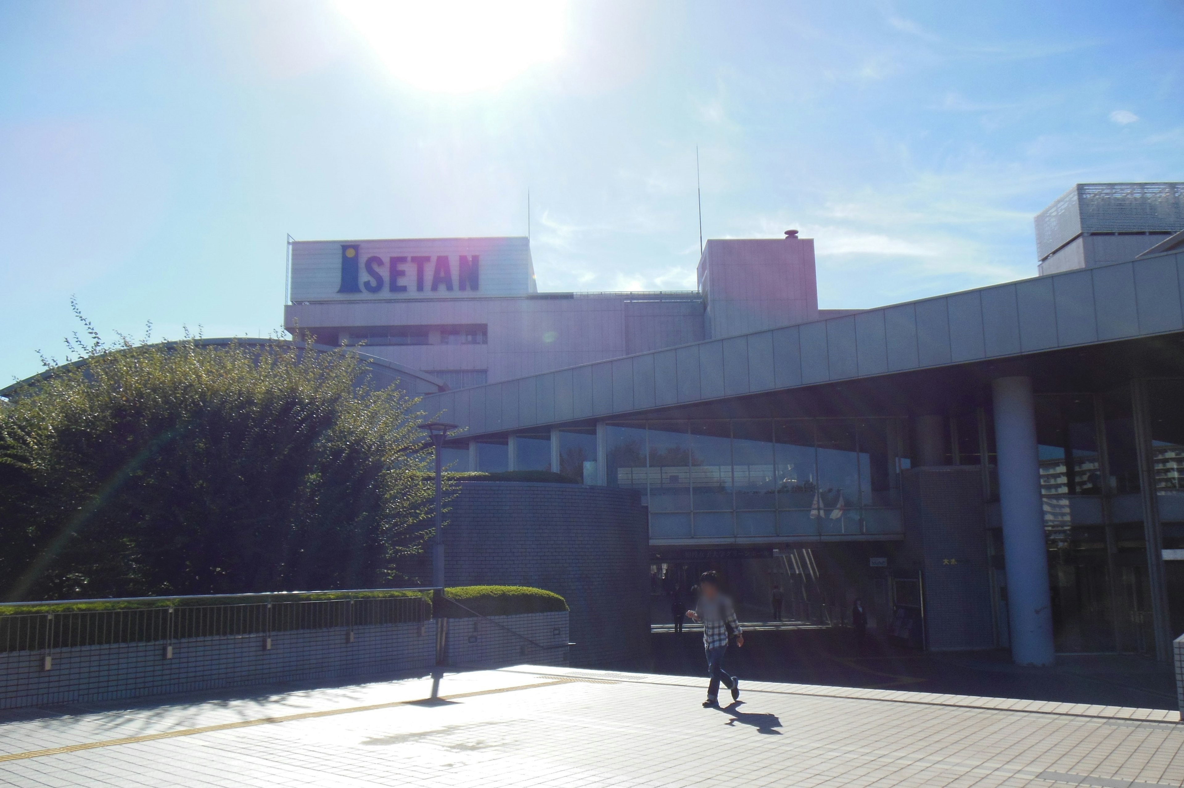 Vista esterna del edificio Isetan con una persona che cammina sotto un cielo blu