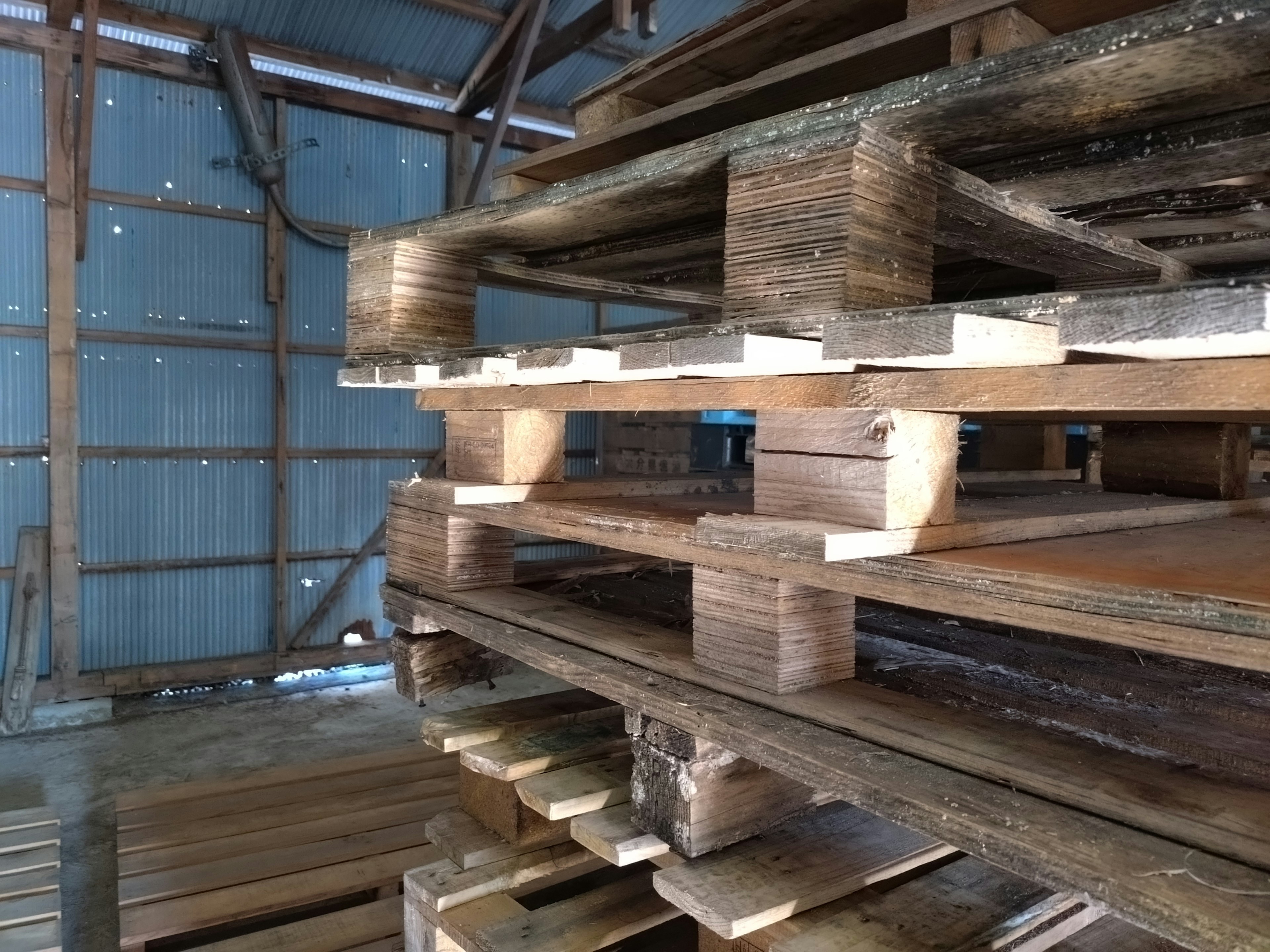 Image de palettes en bois empilées à l'intérieur d'un entrepôt