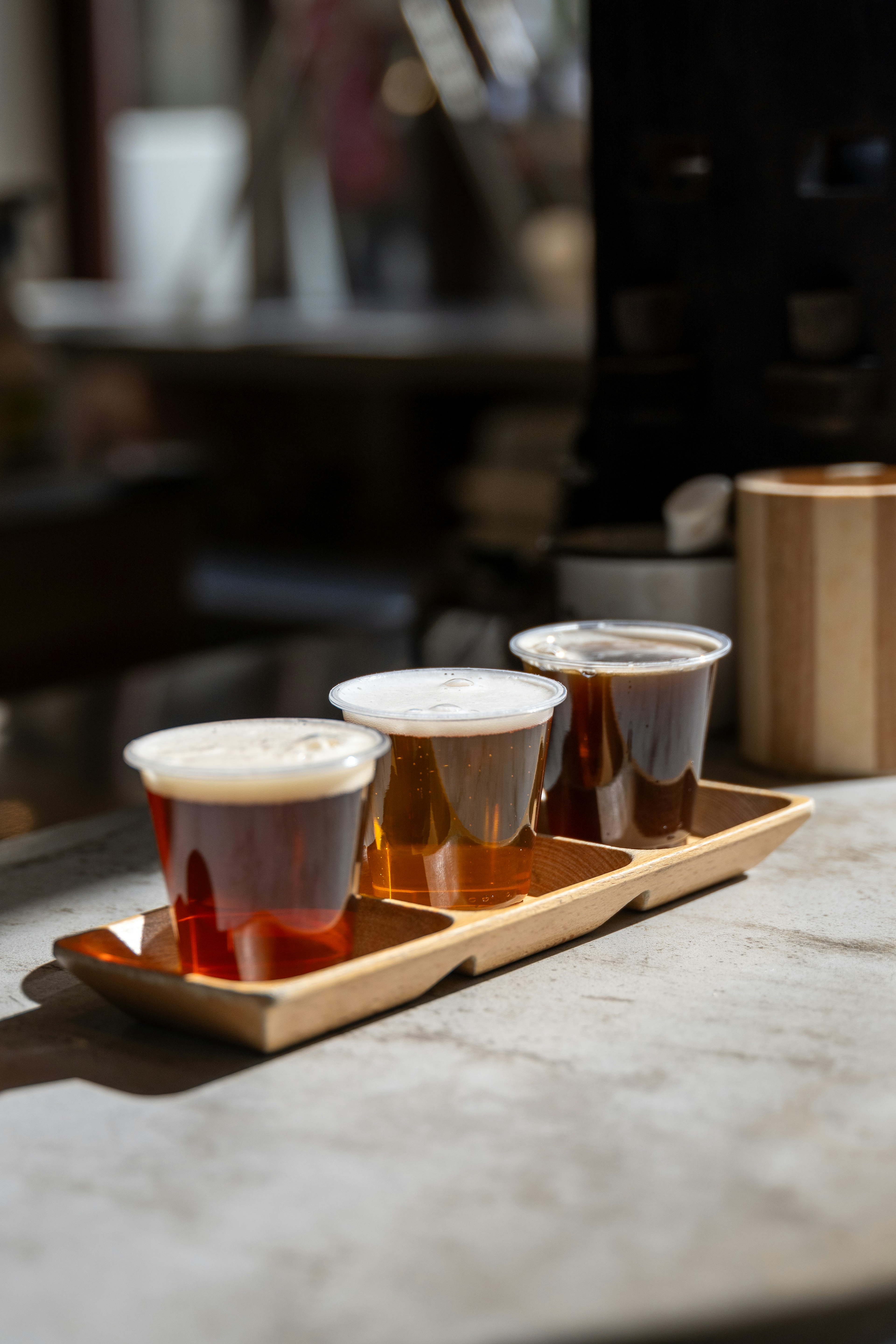 A flight of three beer samples on a wooden tray