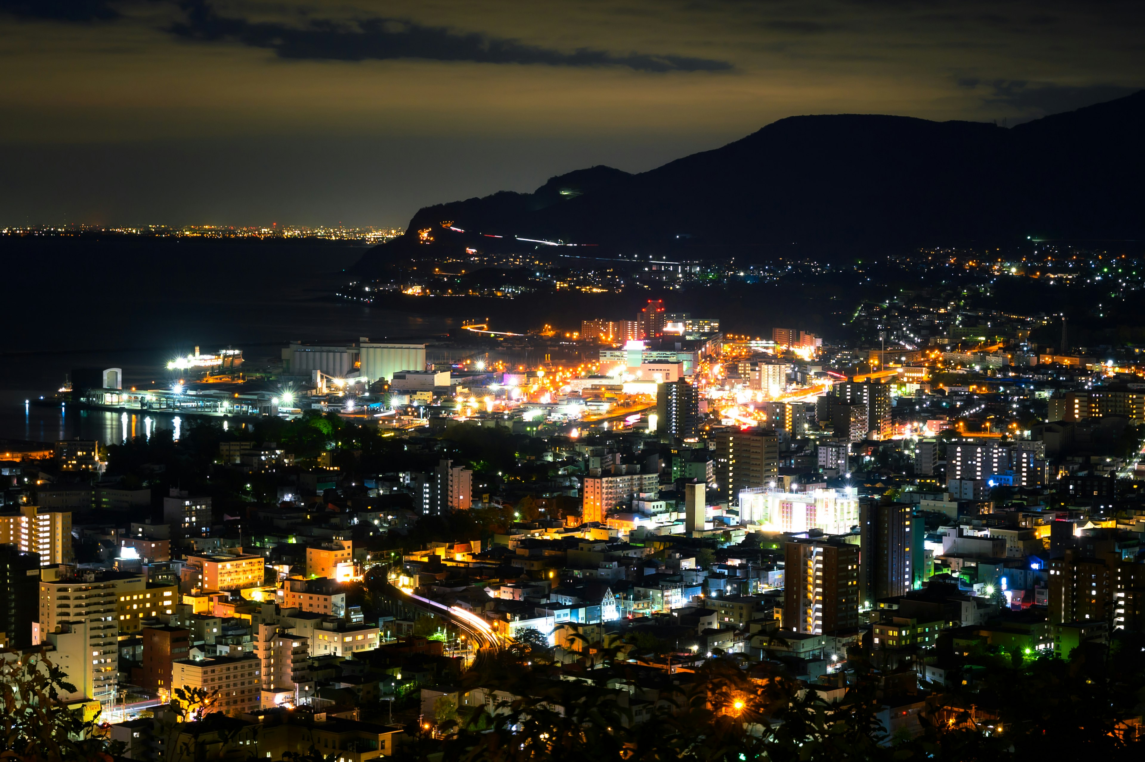 Beautiful night view of a cityscape with bright buildings and shimmering sea lights