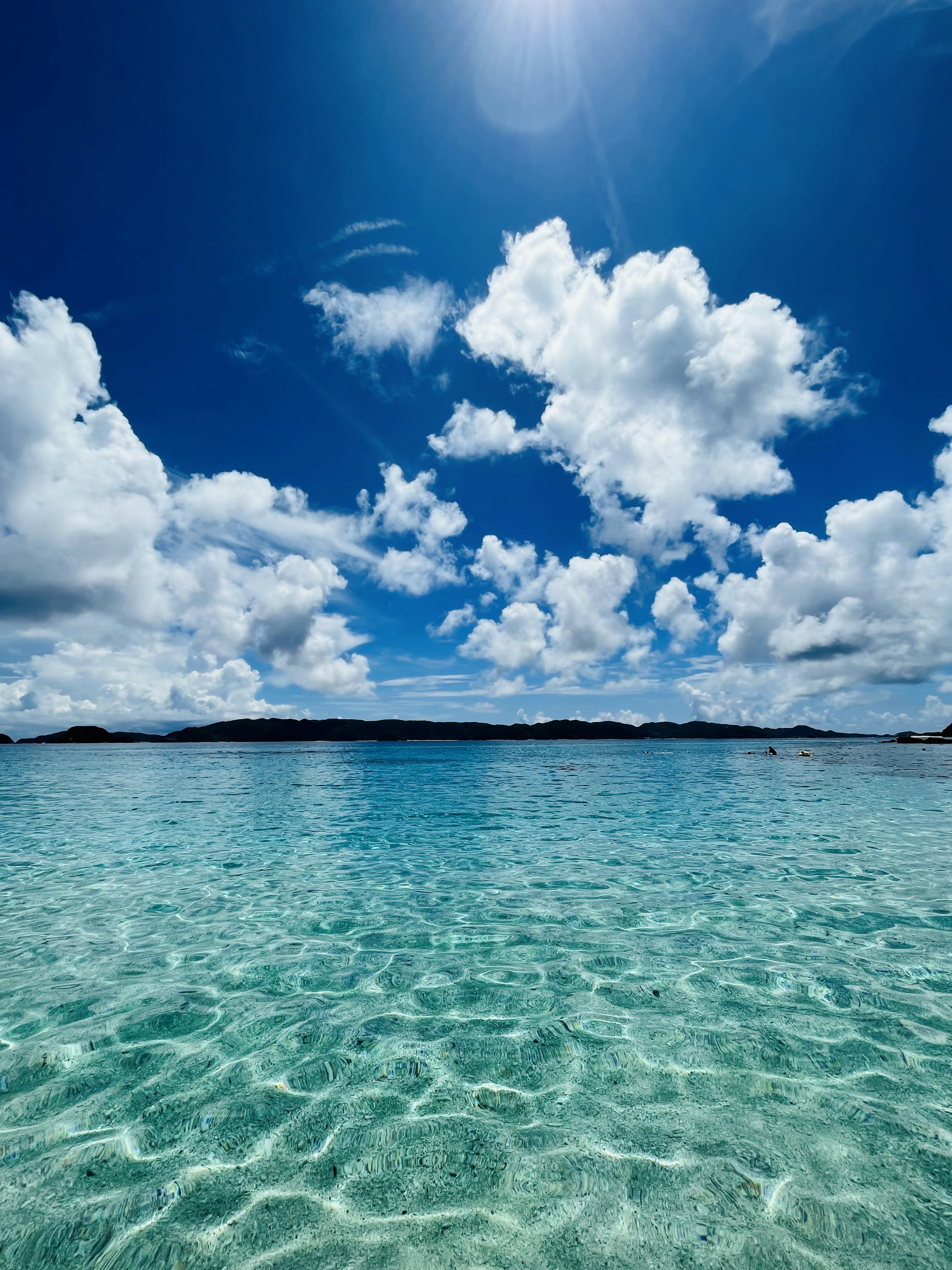 Une vue sereine de l'océan avec une eau turquoise claire et des nuages blancs duveteux