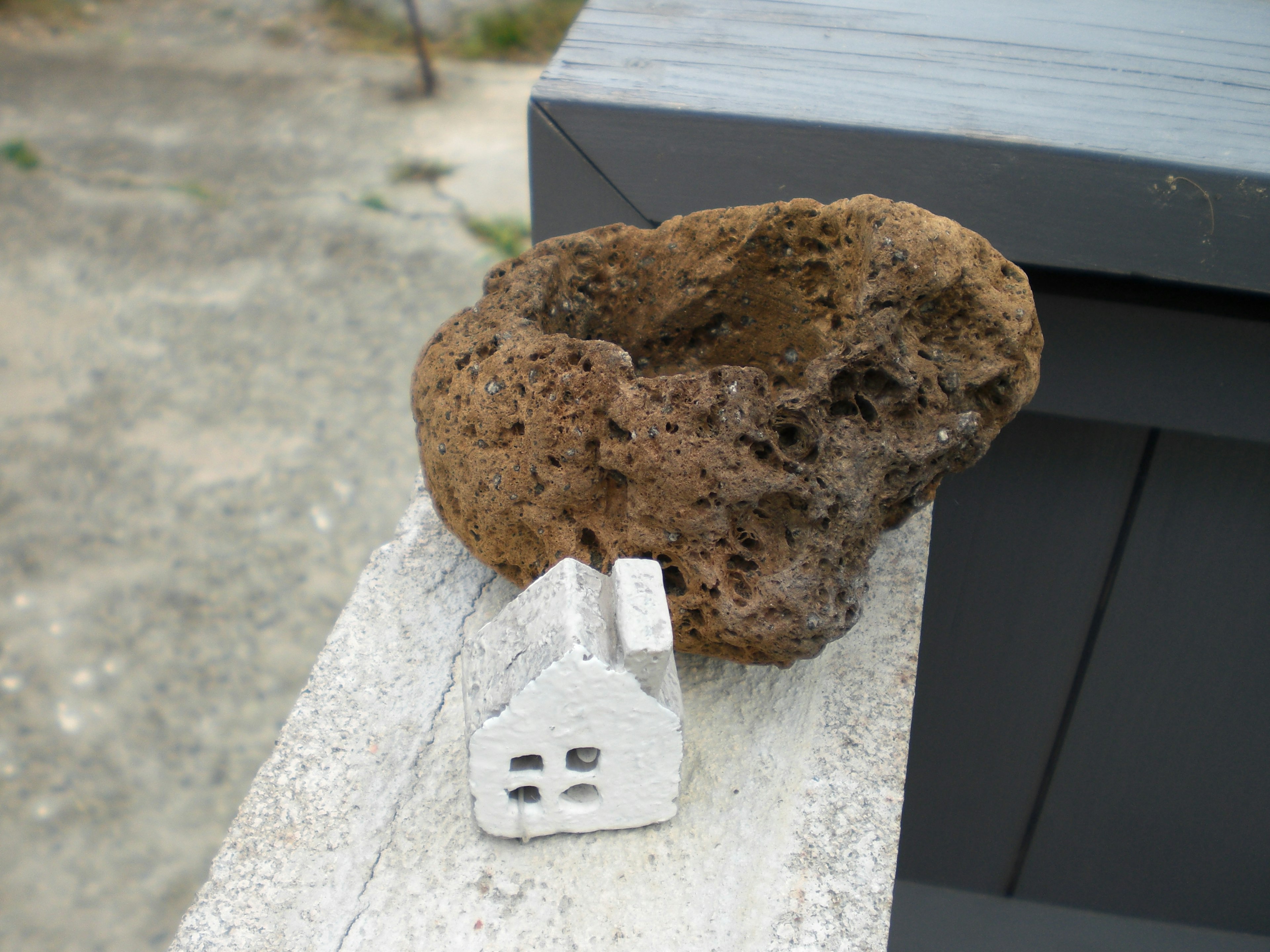 A small white house model next to a large rock-like object