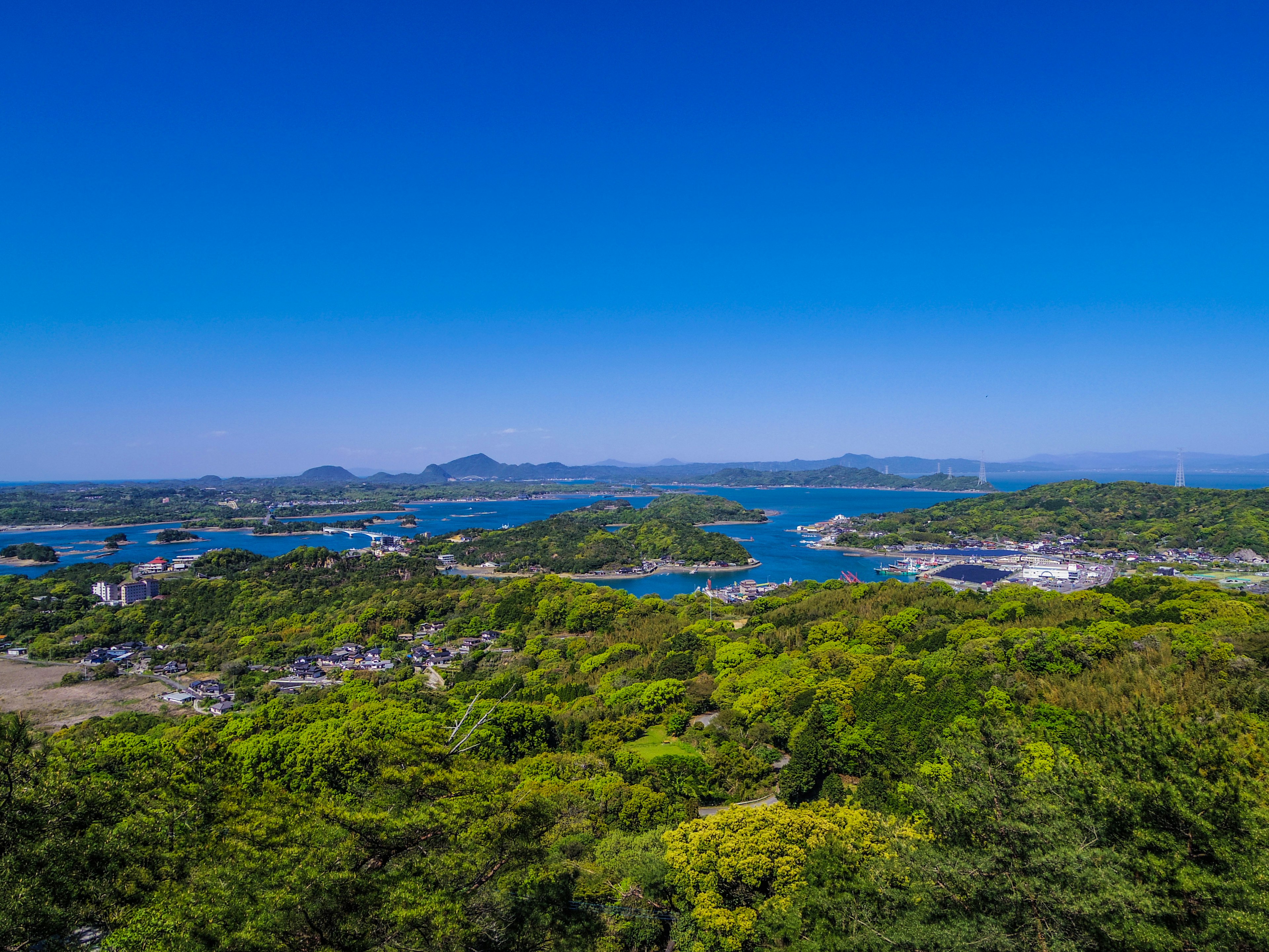 在晴朗的天空下，郁郁蔥蔥的綠色島嶼和藍色水域的全景