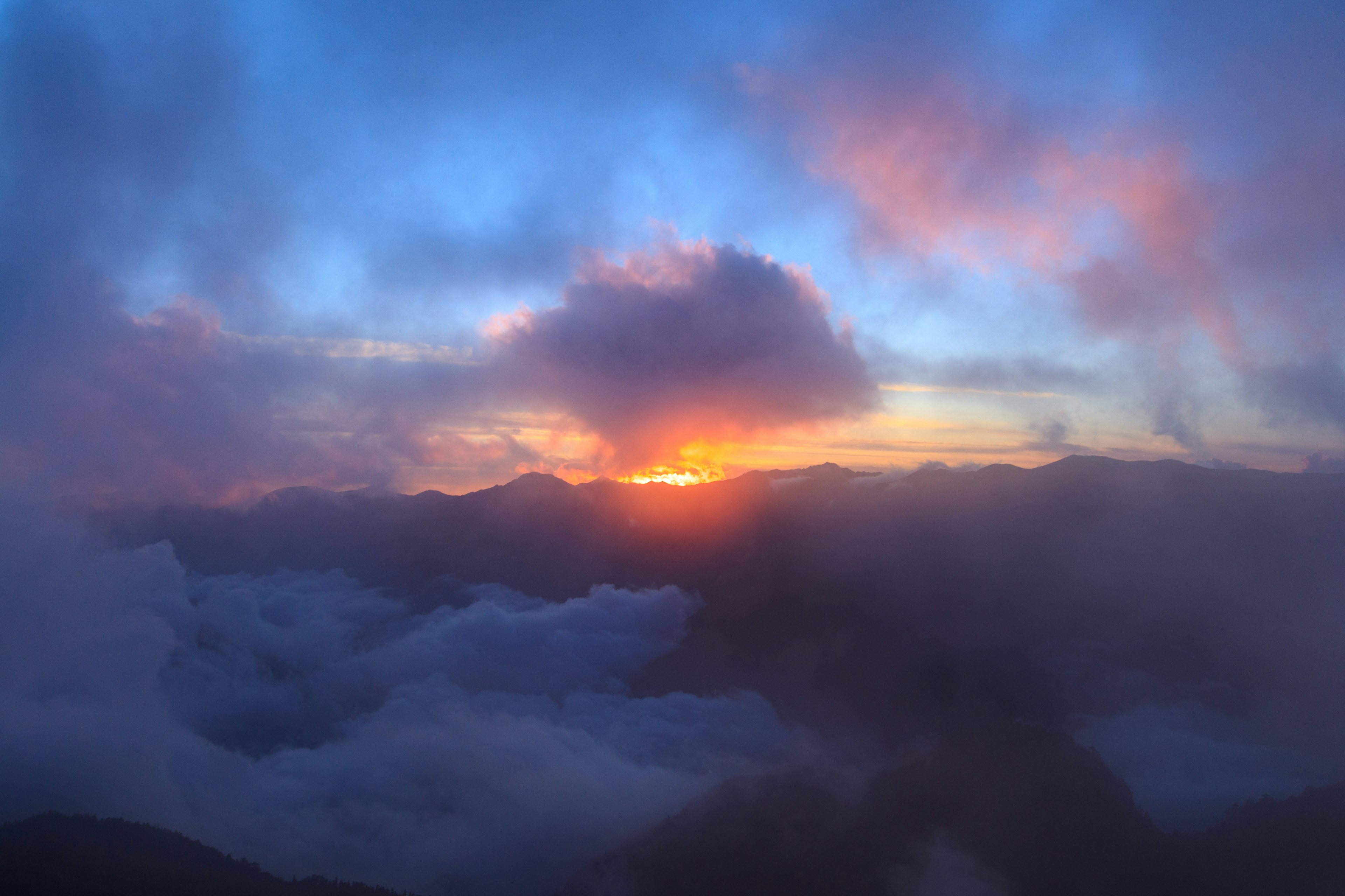 山々の間から昇る美しい夕日と雲