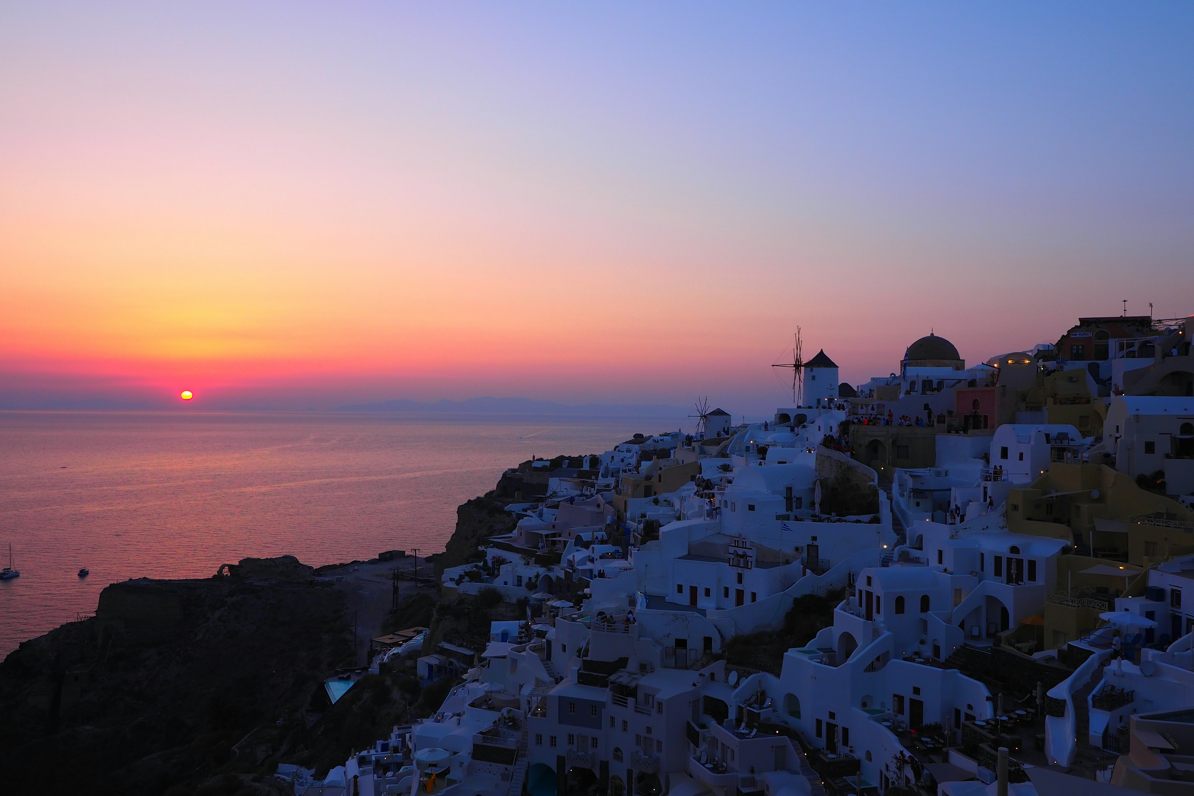 Vista del tramonto a Santorini con edifici bianchi e mare sereno