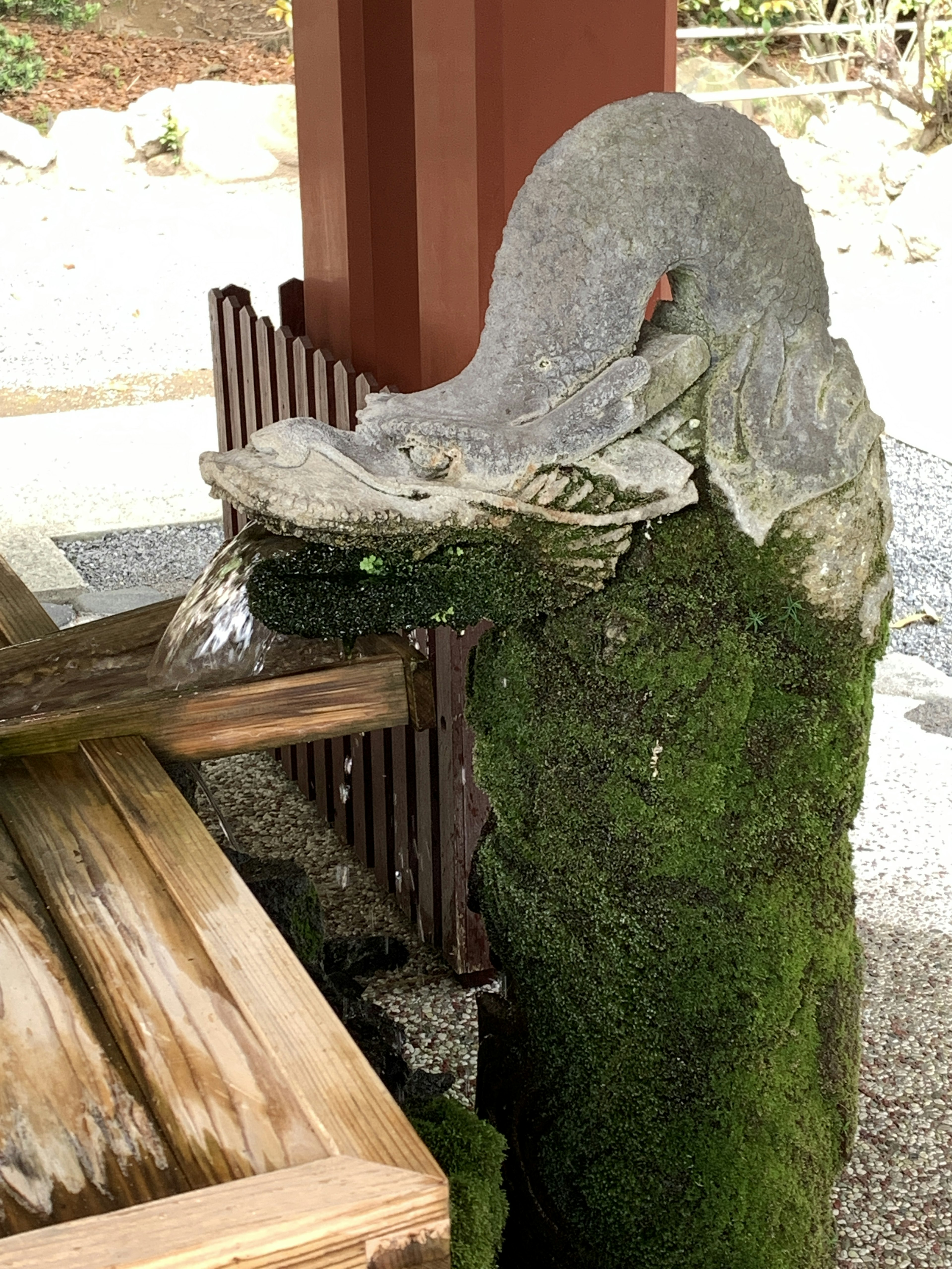 Moss-covered stone sculpture with wooden table in a serene setting