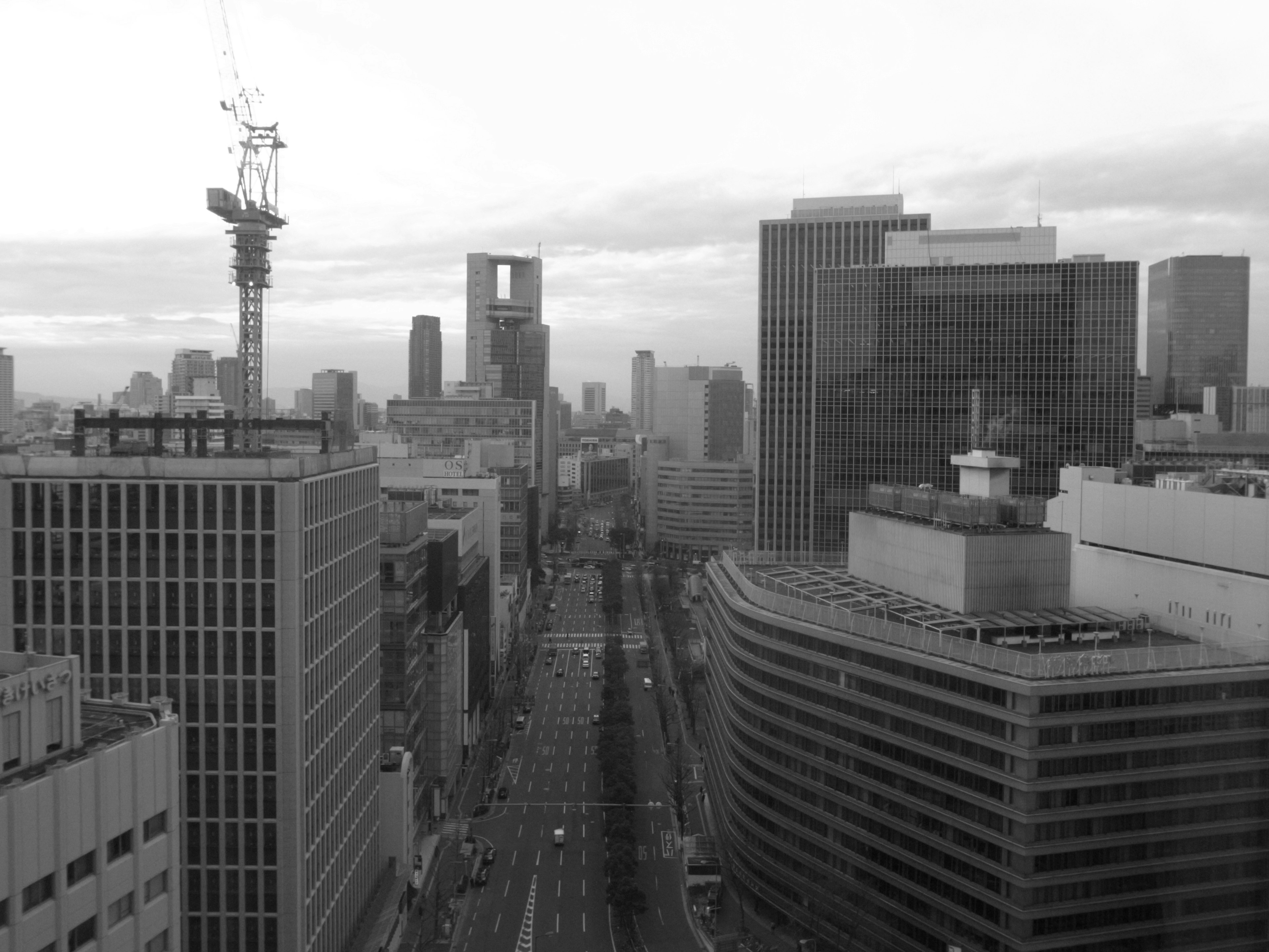 Foto monokrom dari cakrawala Tokyo dengan gedung-gedung tinggi dan jalan lebar