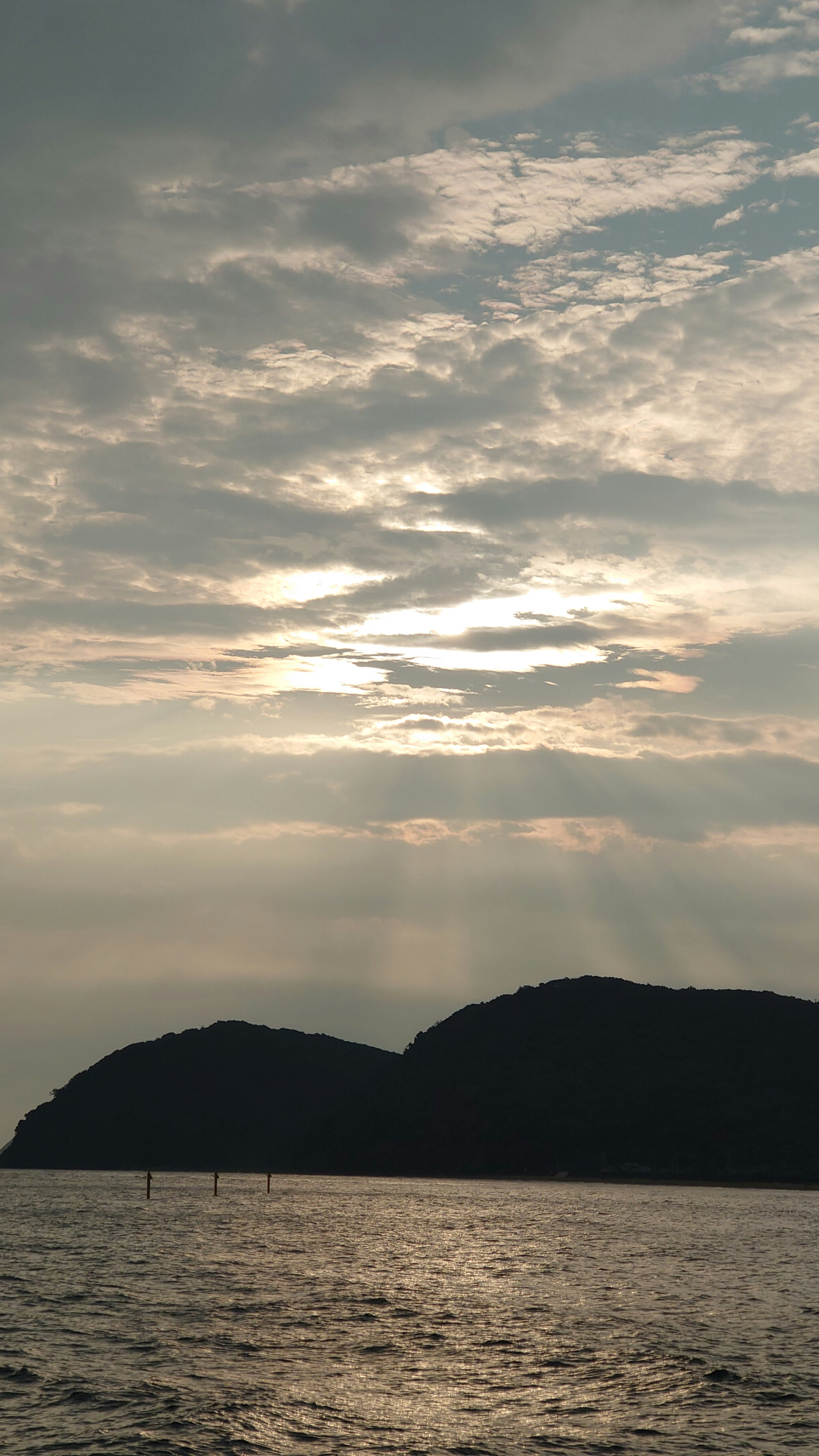 Paisaje con montañas sobre el mar y cielo nublado