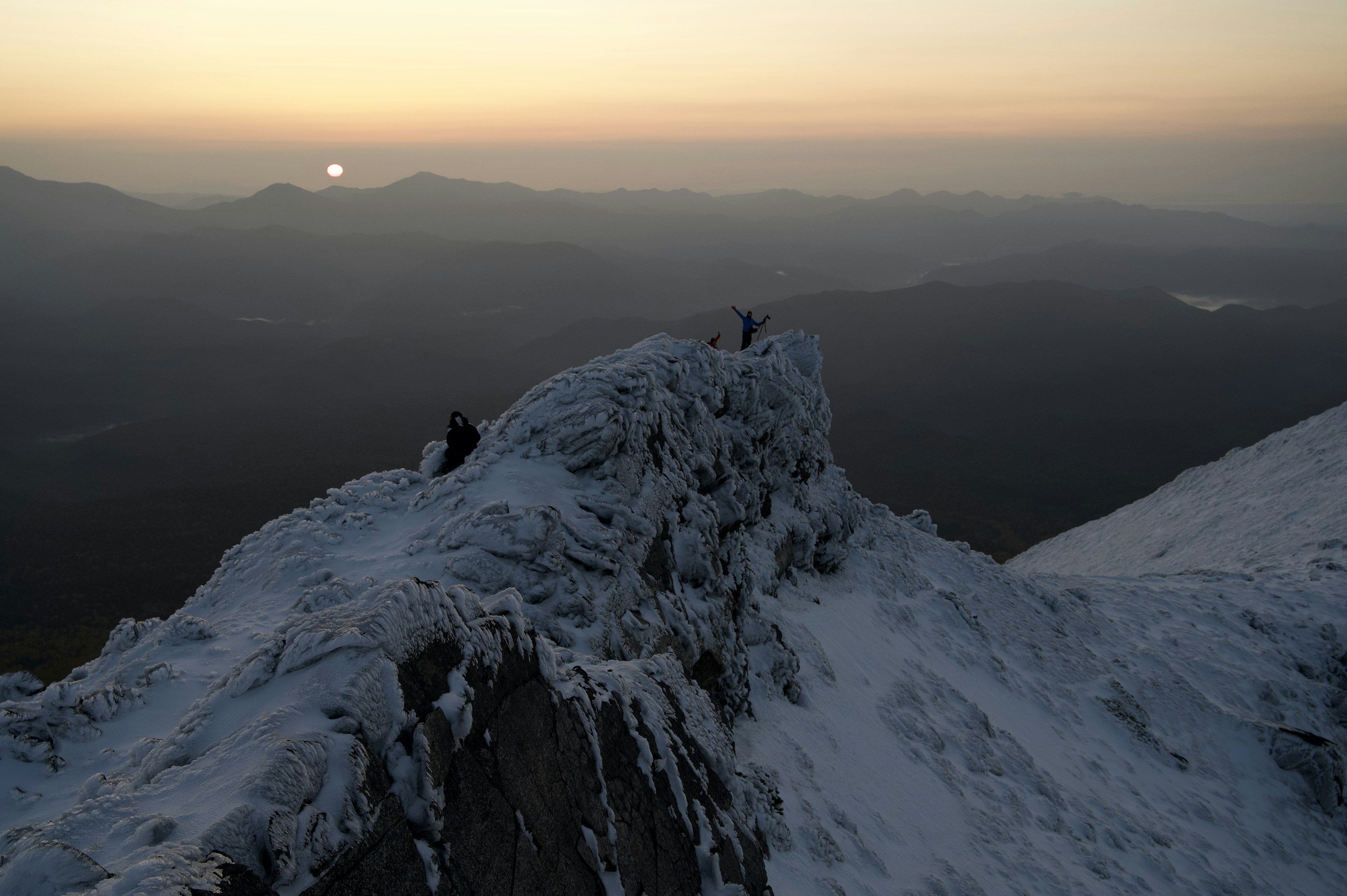 雪に覆われた山頂からの美しい夕日と遠くの山々