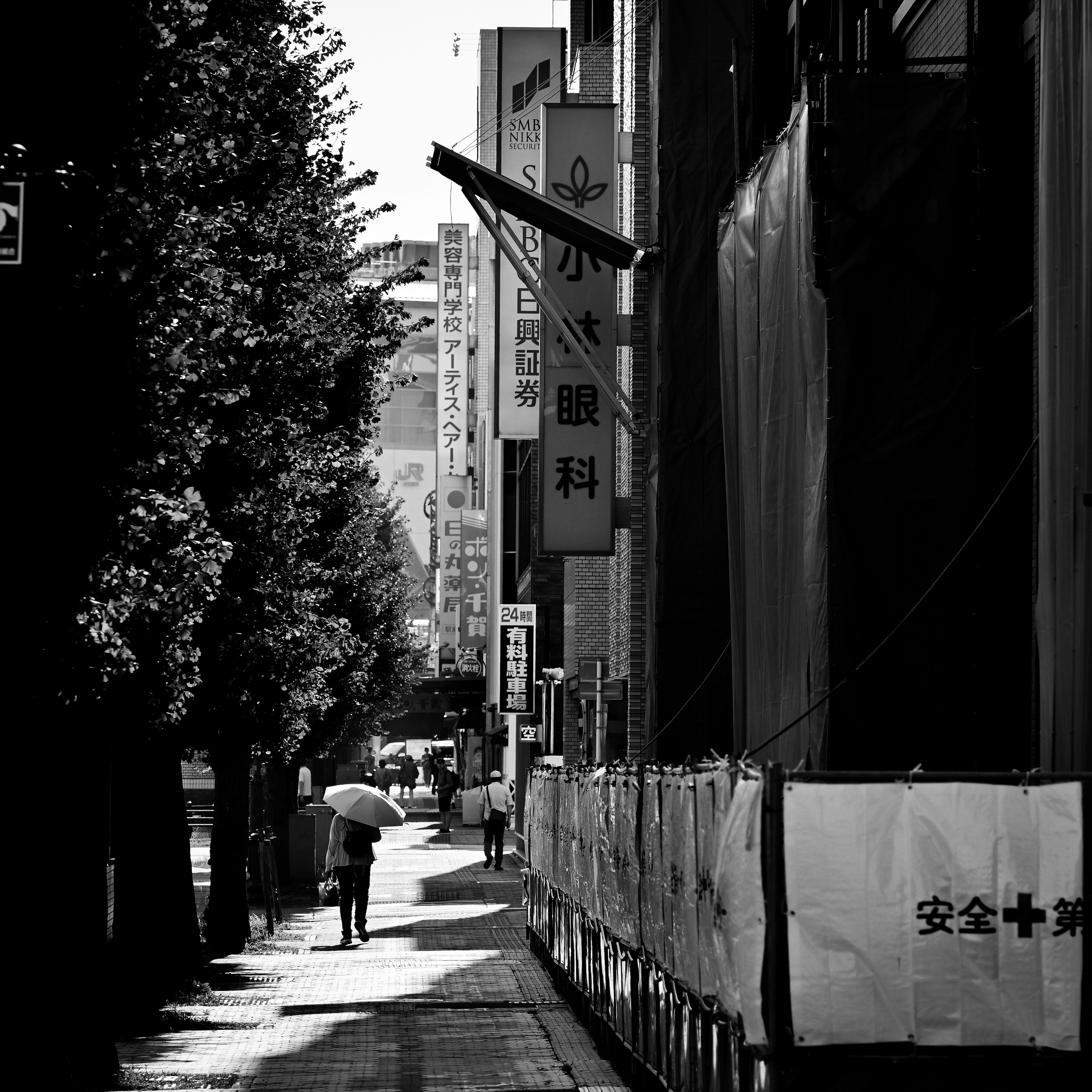 Una persona caminando con un paraguas en un entorno urbano en blanco y negro