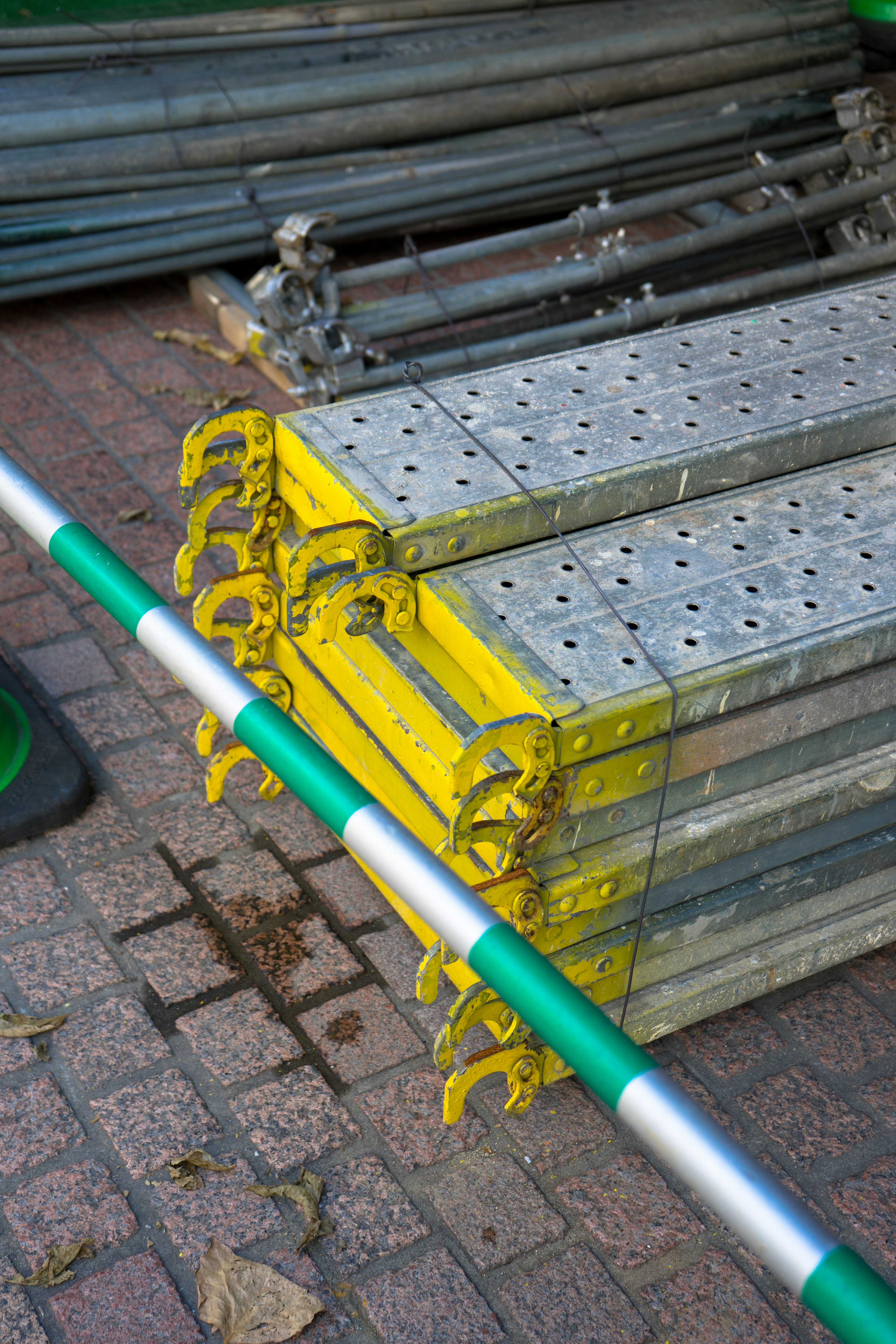 Stacked metal ladders in yellow and silver resting on a brick surface