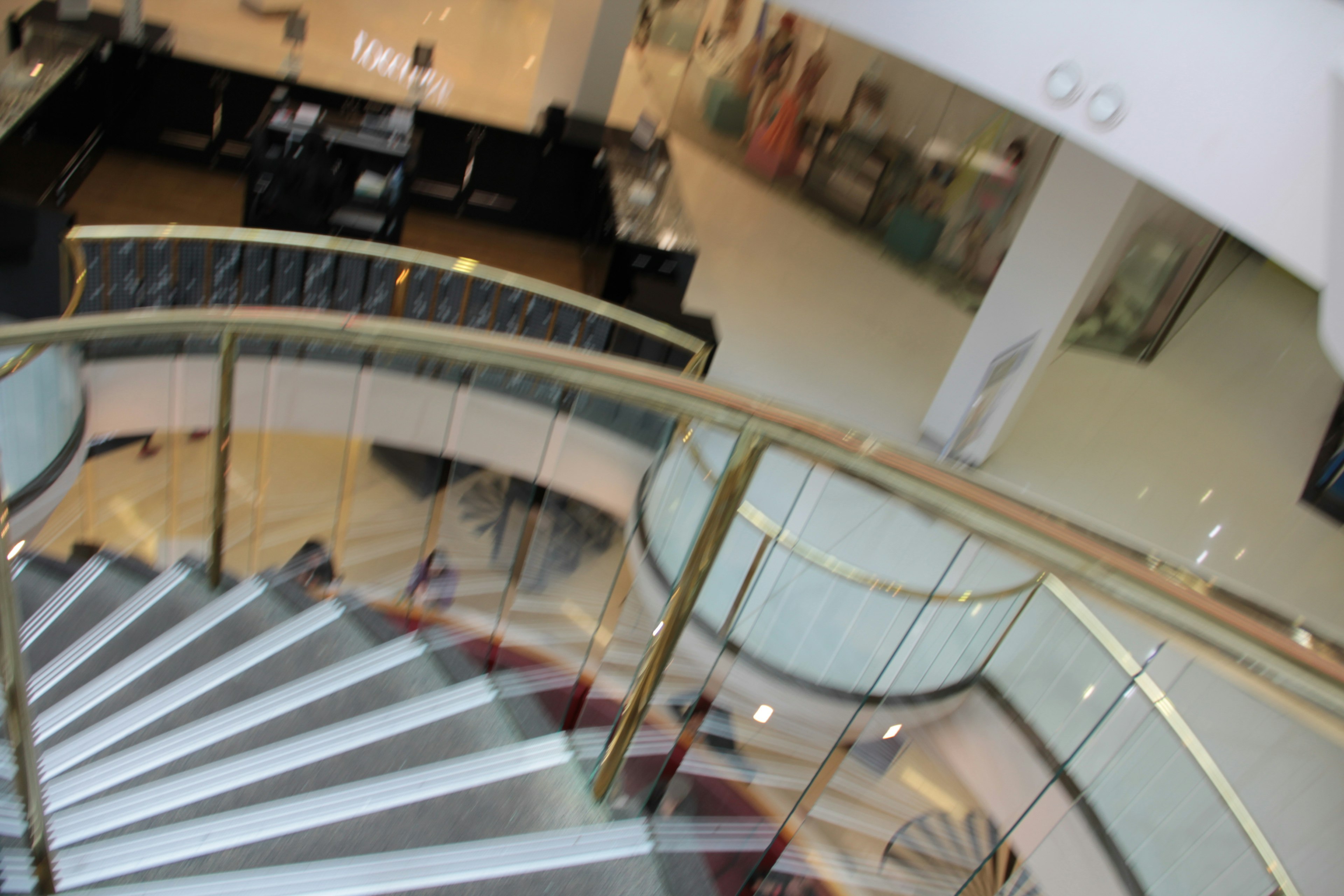 View of a modern spiral staircase with glass railing and elegant interior design