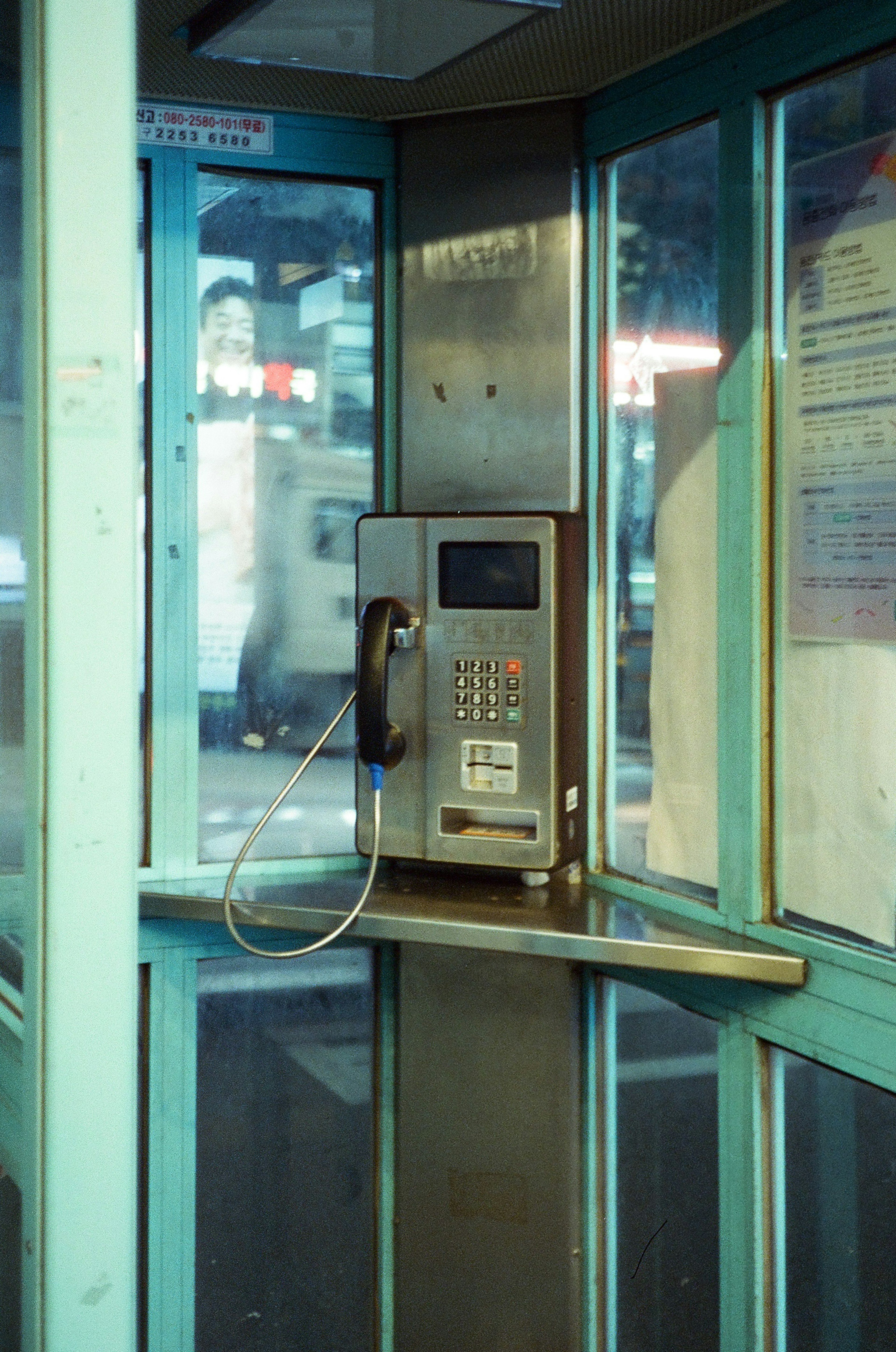 Interno di una cabina telefonica blu con un telefono pubblico