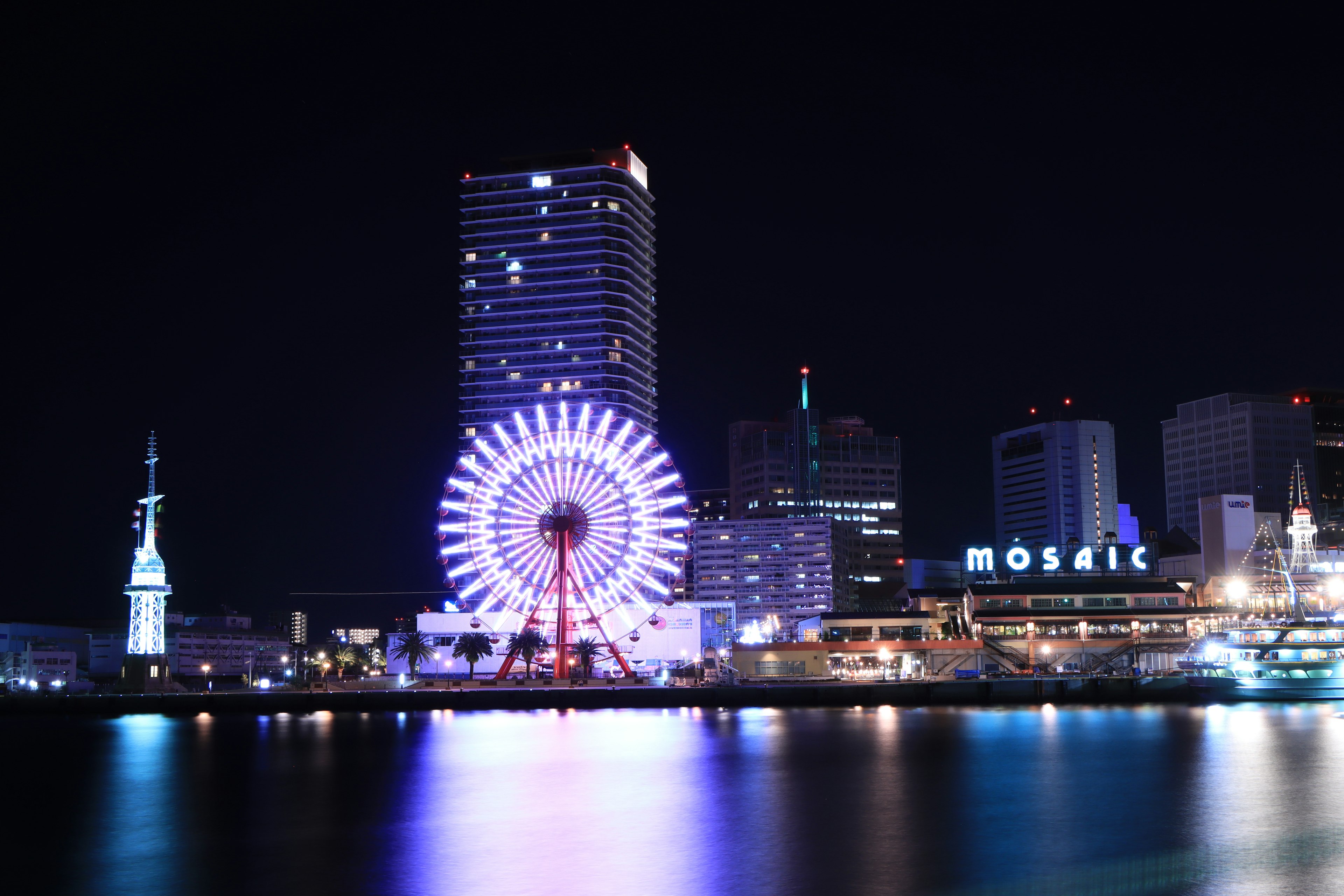 Schöne Aussicht auf ein Riesenrad und Wolkenkratzer am Hafen bei Nacht