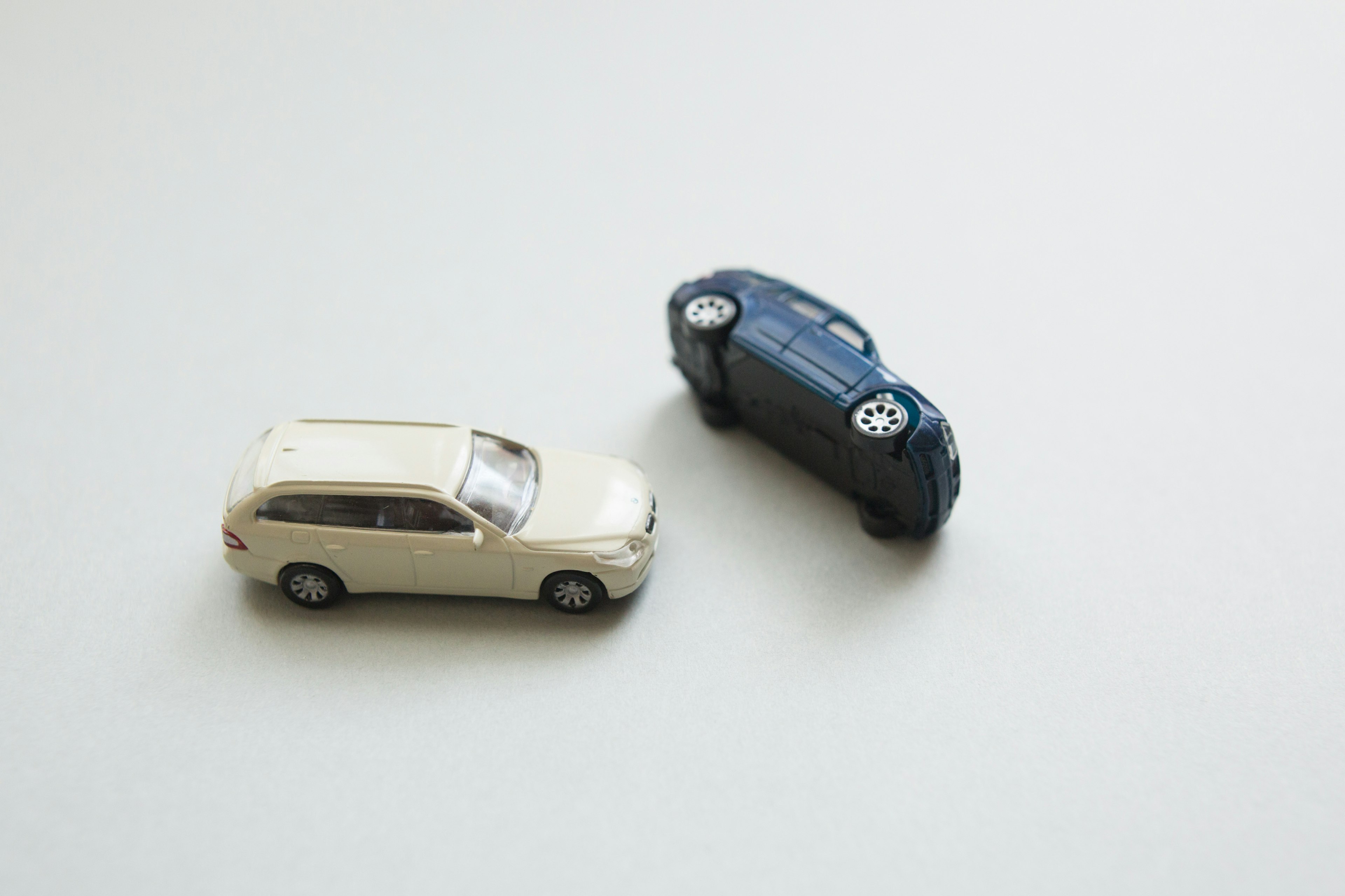 Two toy cars on a plain background one upright and one flipped