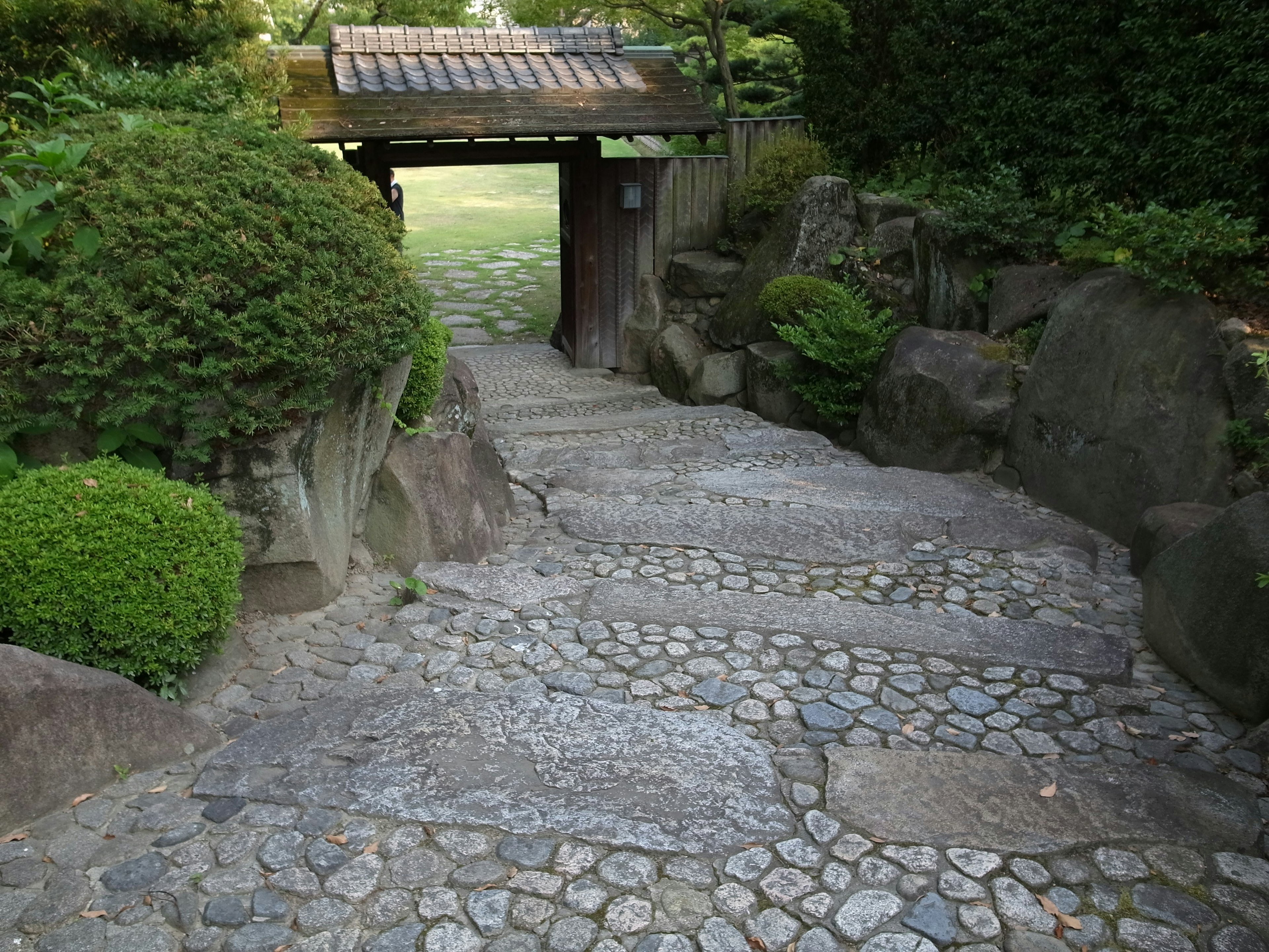 Pflasterweg, der zu einem traditionellen japanischen Garteneingang führt