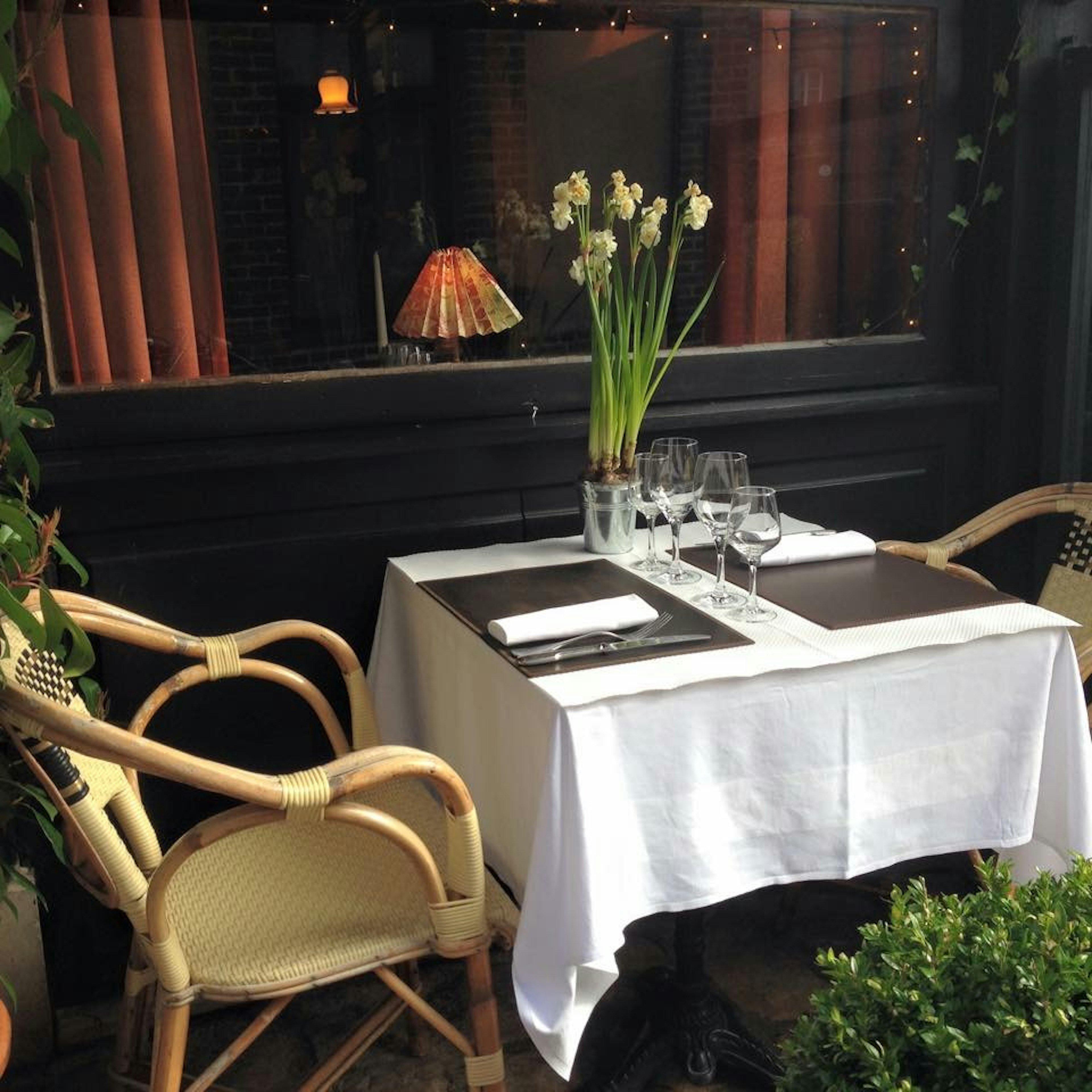 Tavolo da ristorante con tovaglia bianca, bicchieri e vaso di fiori