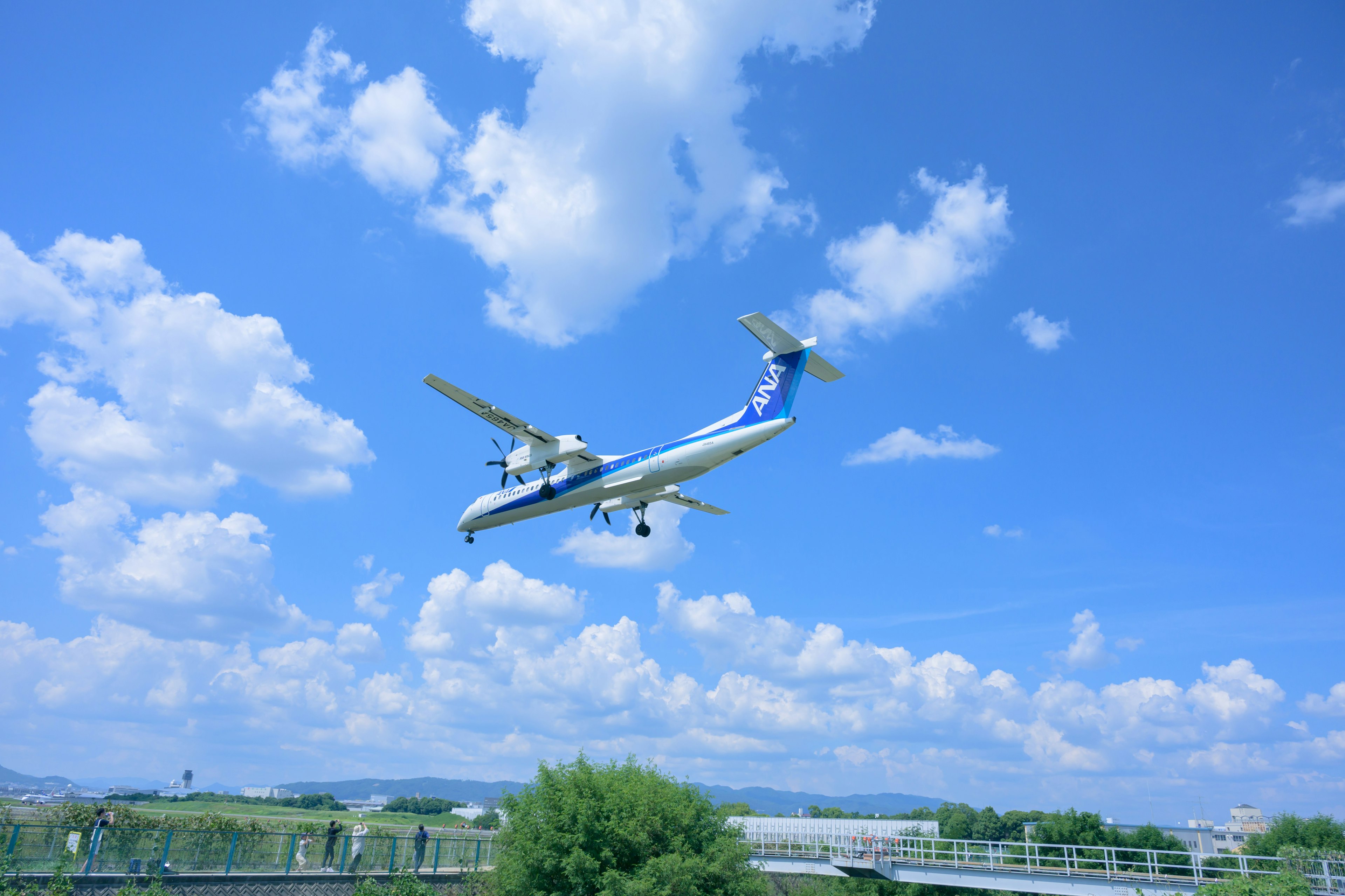 An airplane flying in a bright blue sky with fluffy white clouds