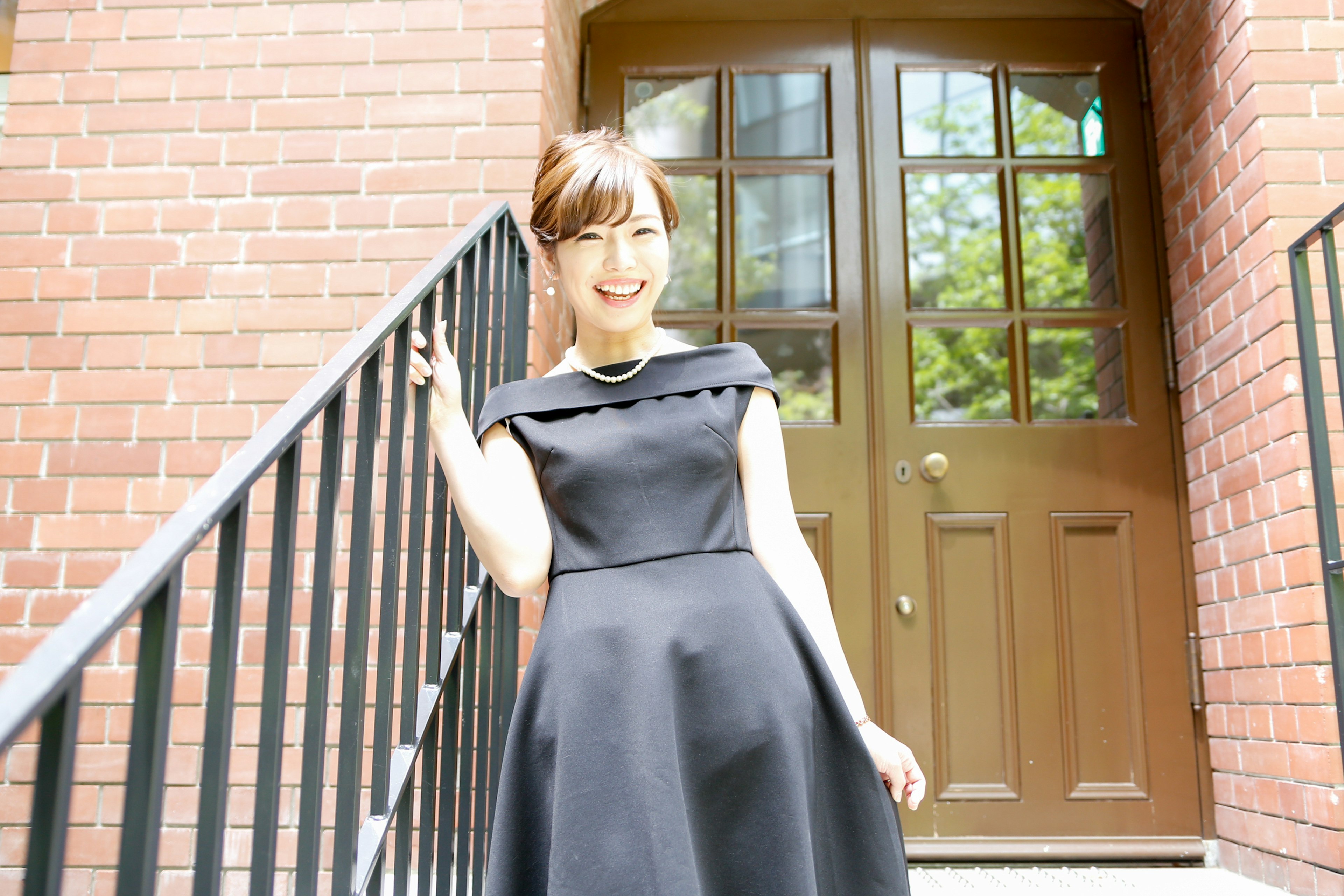 A woman in a black dress standing on a brick staircase