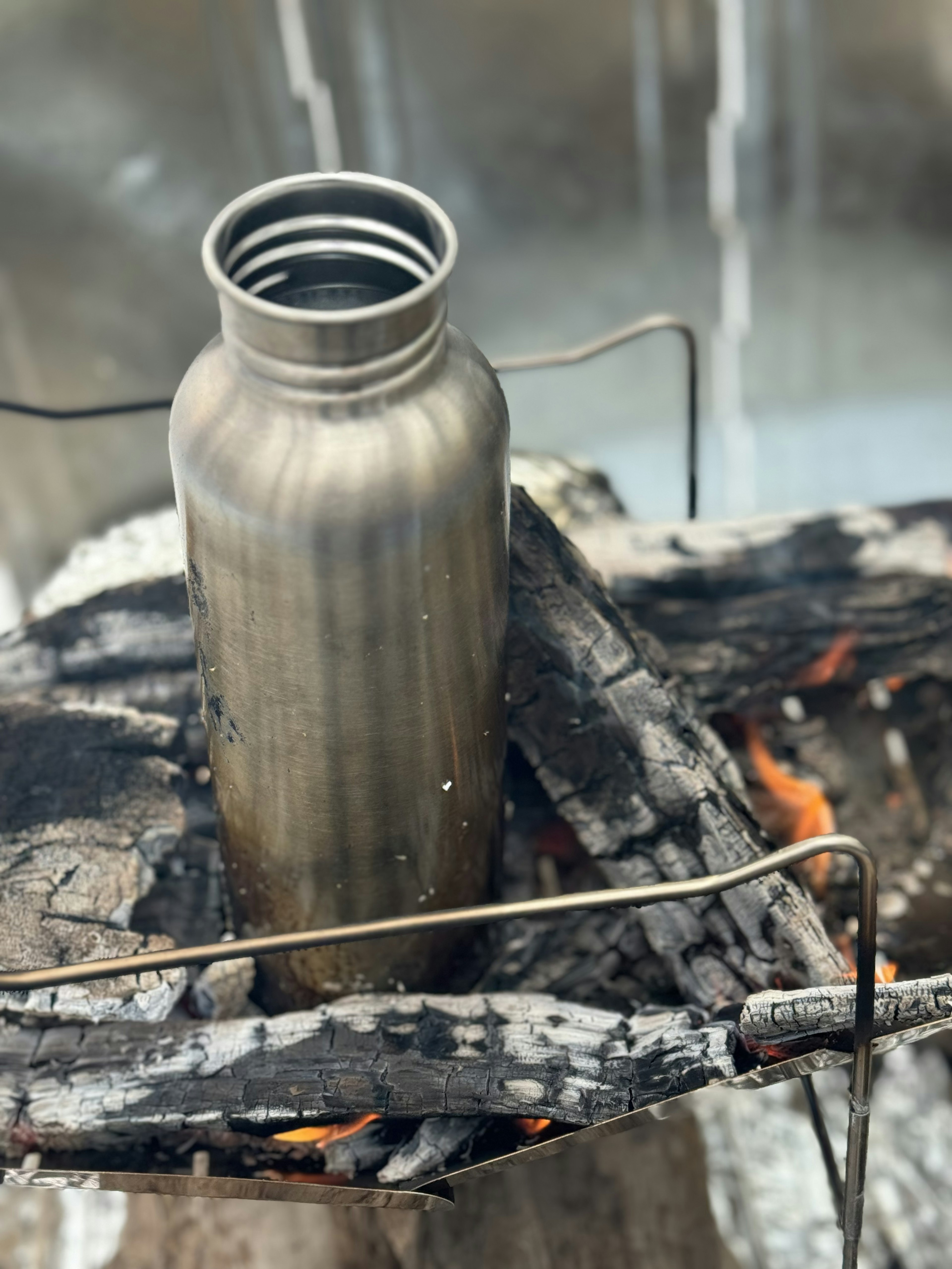 Metallwasserflasche über einem Lagerfeuer platziert