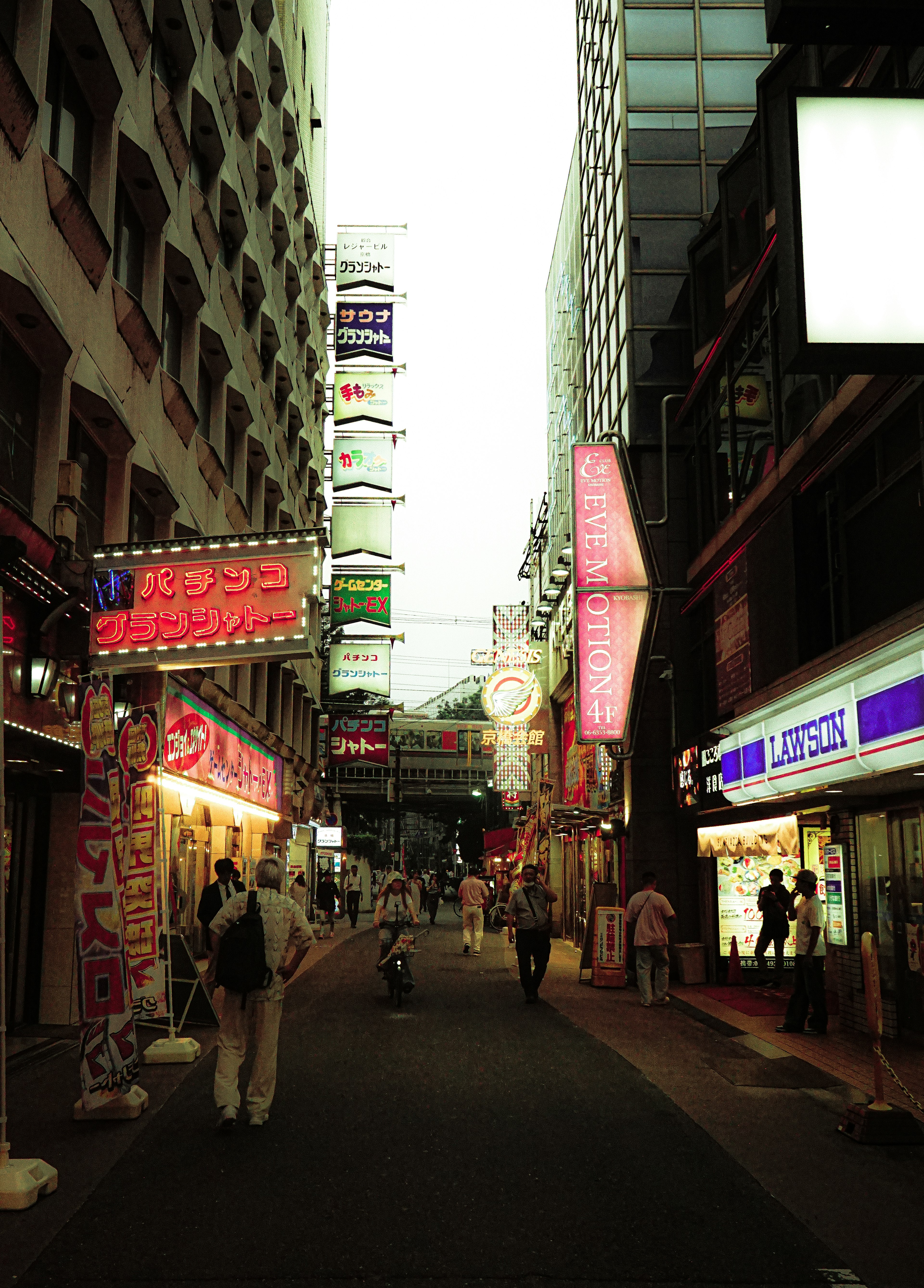 Enge Straße in Tokio mit Neonreklamen und Menschen