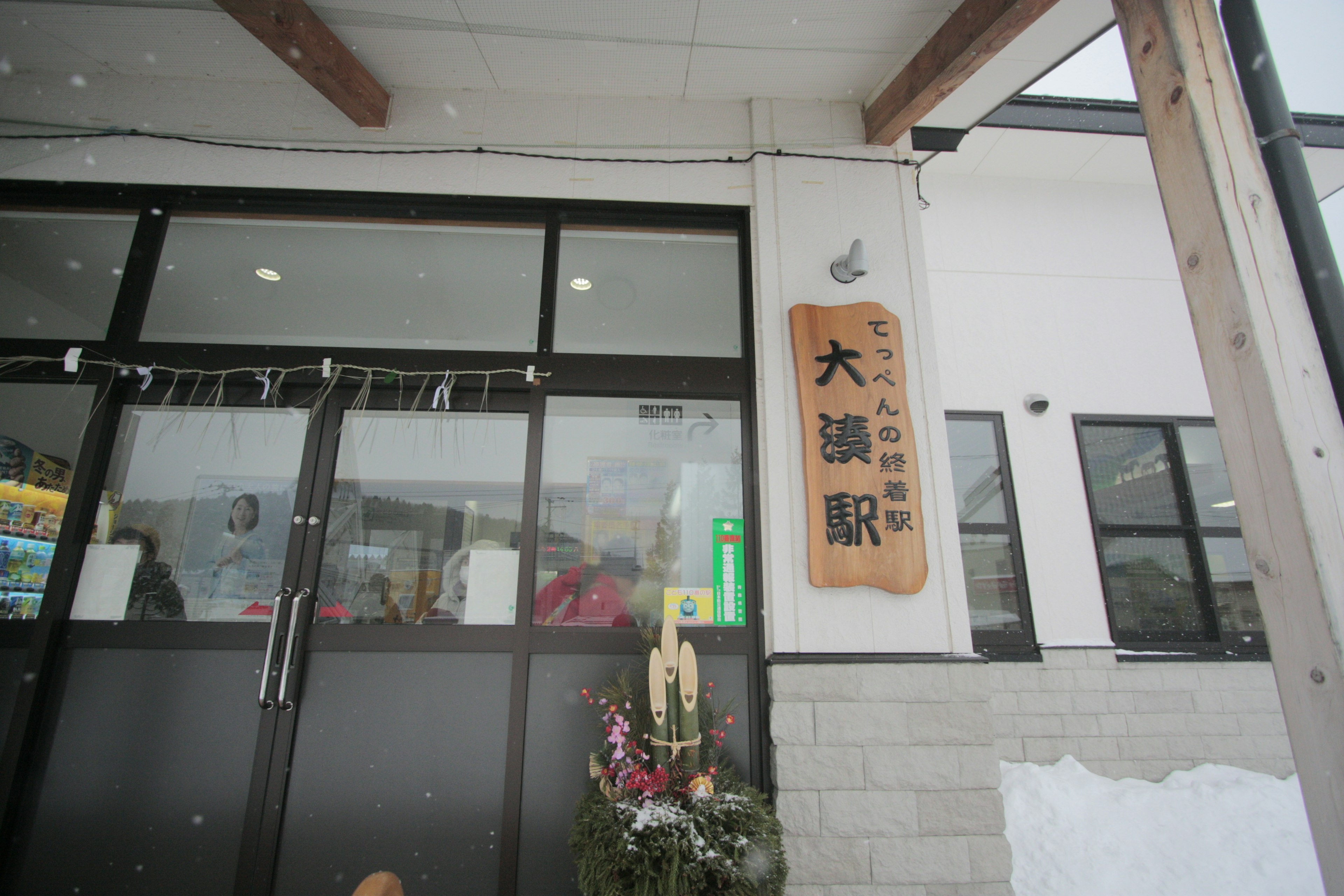 Exterior view of Oumi Station with its sign in the snow