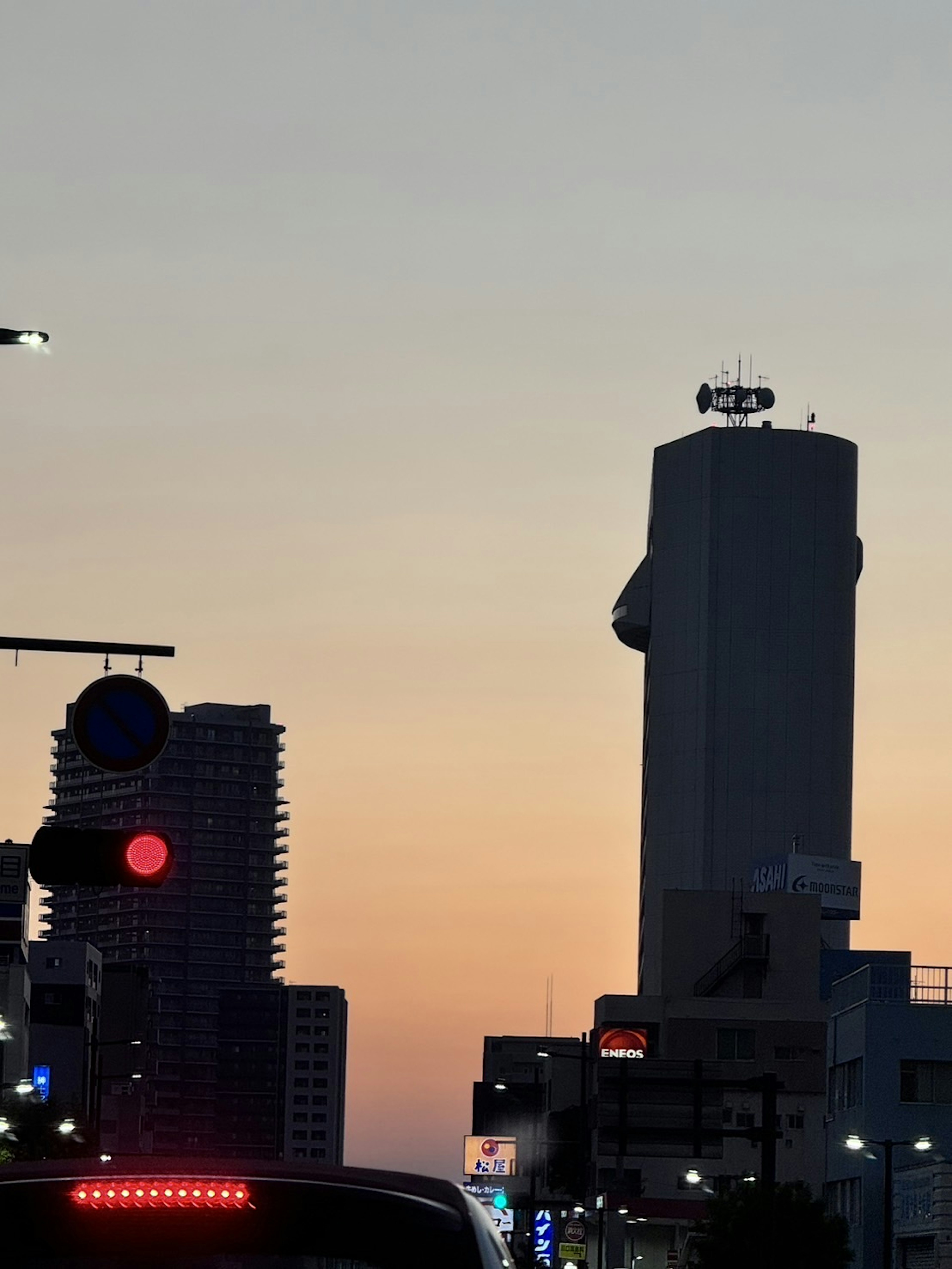 夕陽下的摩天大樓輪廓與紅色交通信號燈