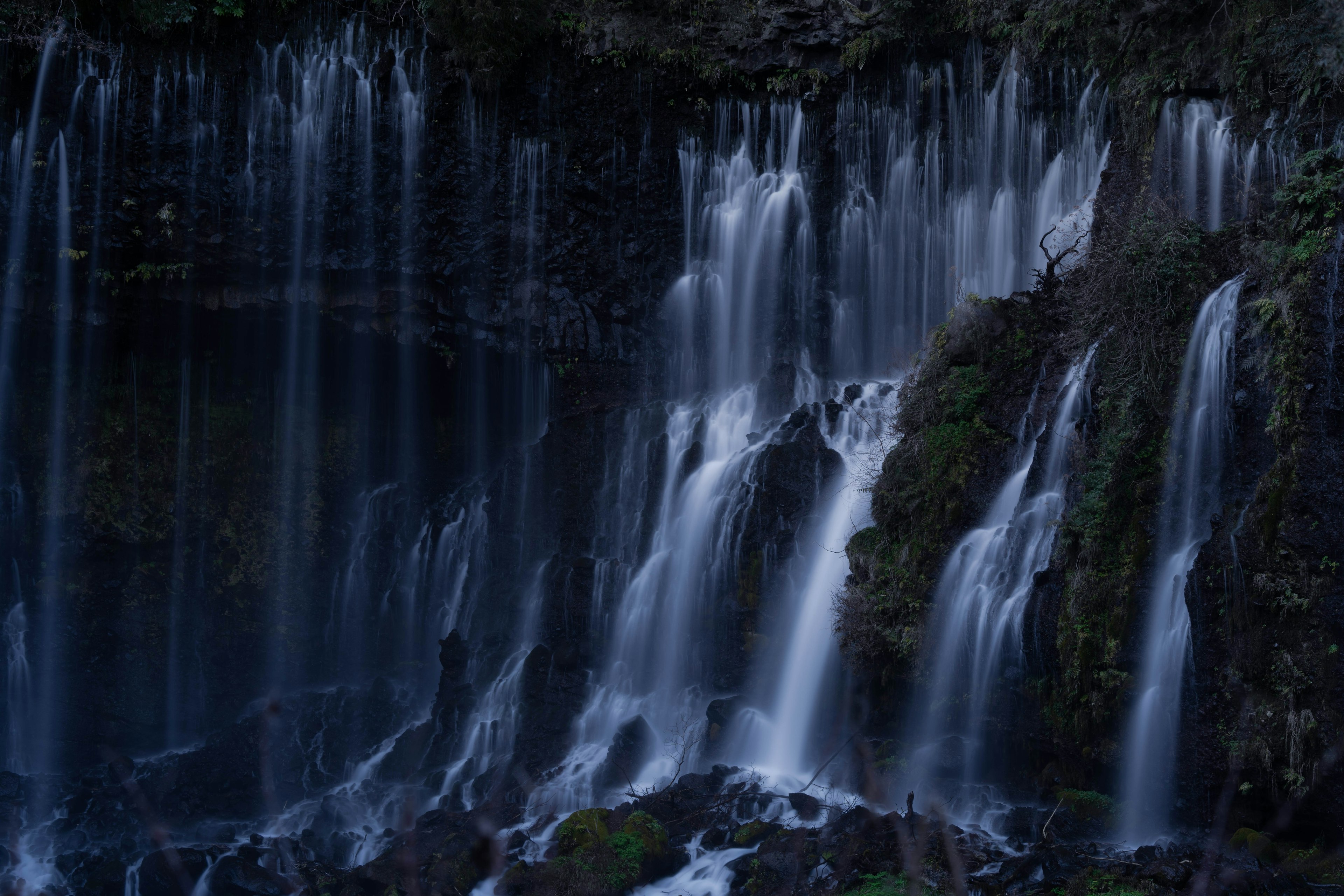 Air terjun indah mengalir di lingkungan gelap