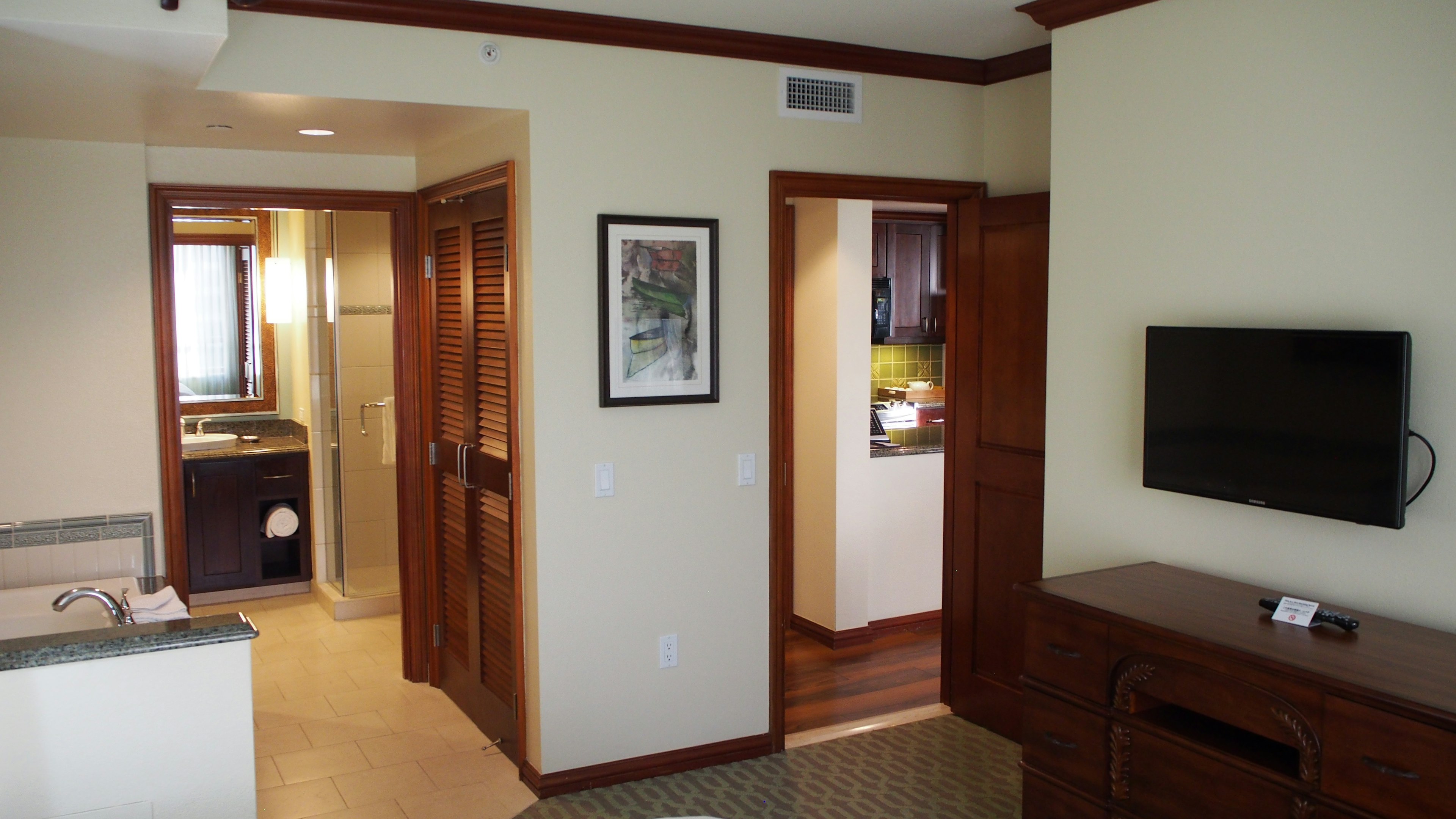 Sala de estar luminosa y área de cocina con puertas de madera y muebles TV montados en la pared