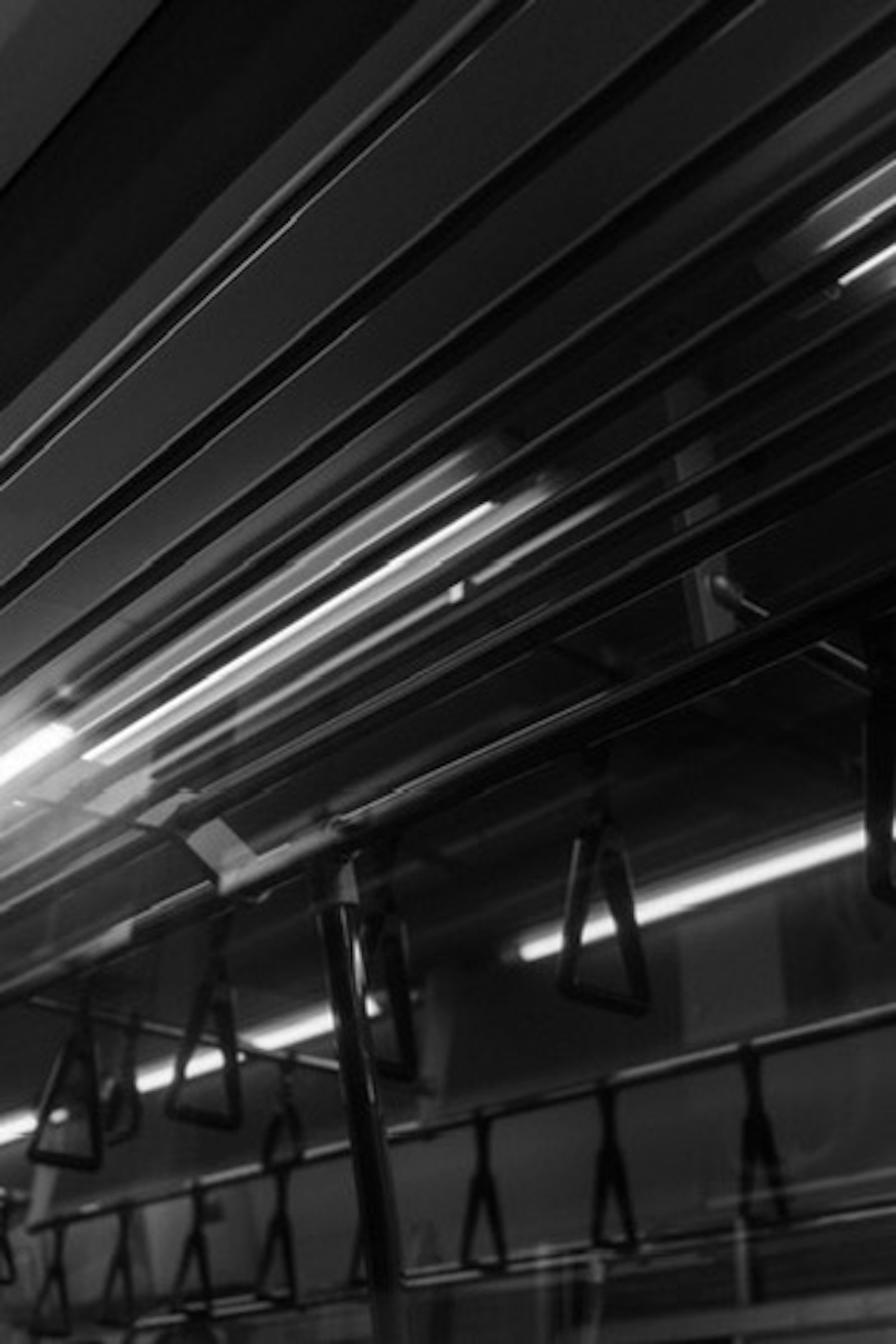 Interior of a subway train in black and white with hanging straps