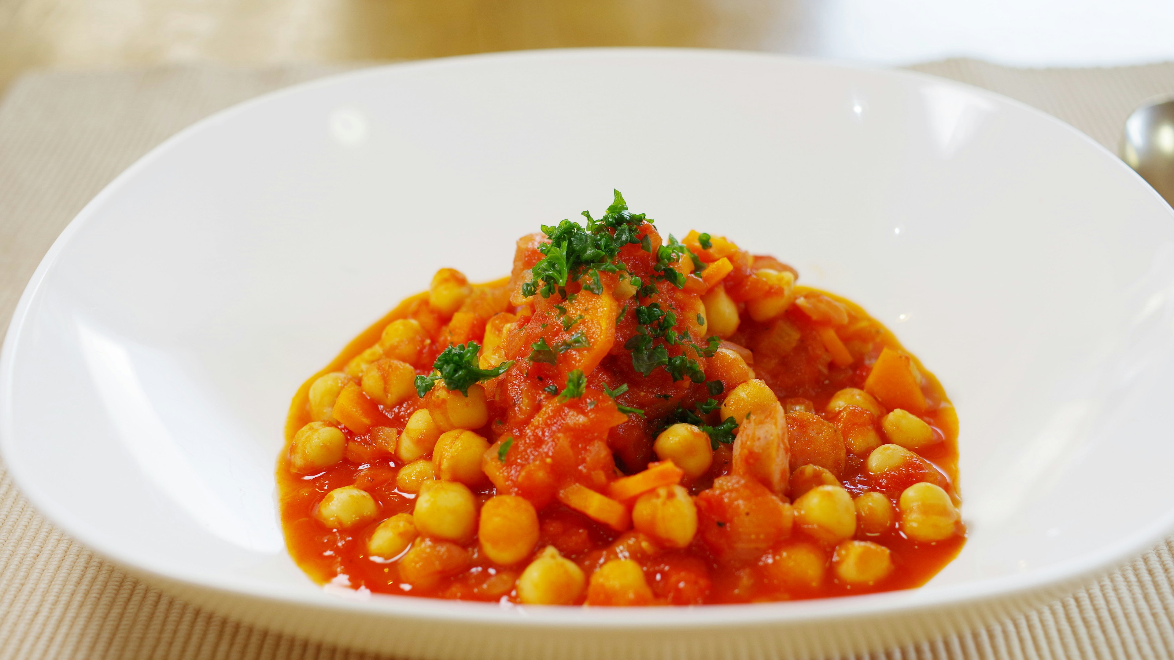 Plat de pois chiches dans une sauce tomate garni de persil sur une assiette blanche