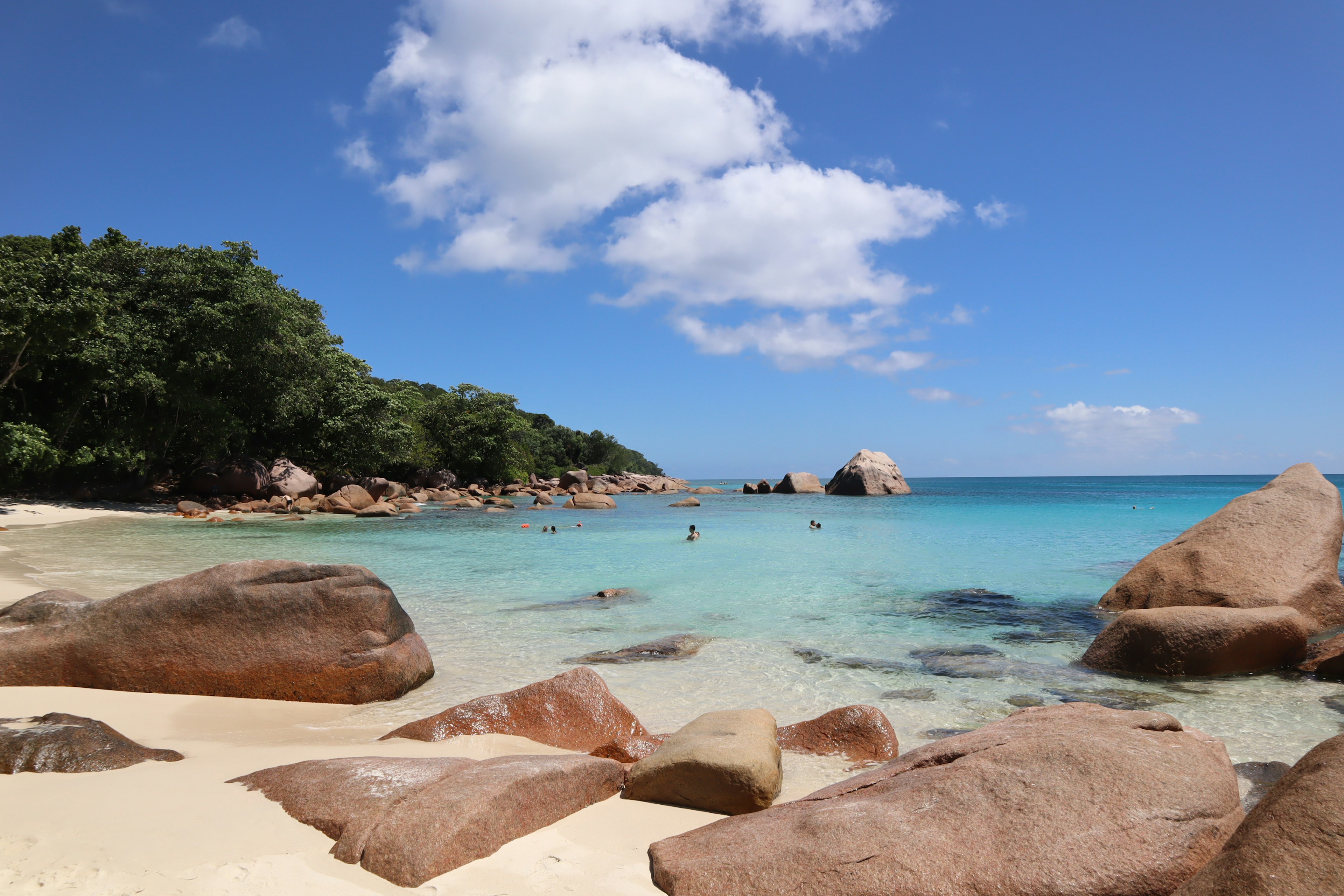 Vista de playa escénica con agua azul y grandes rocas