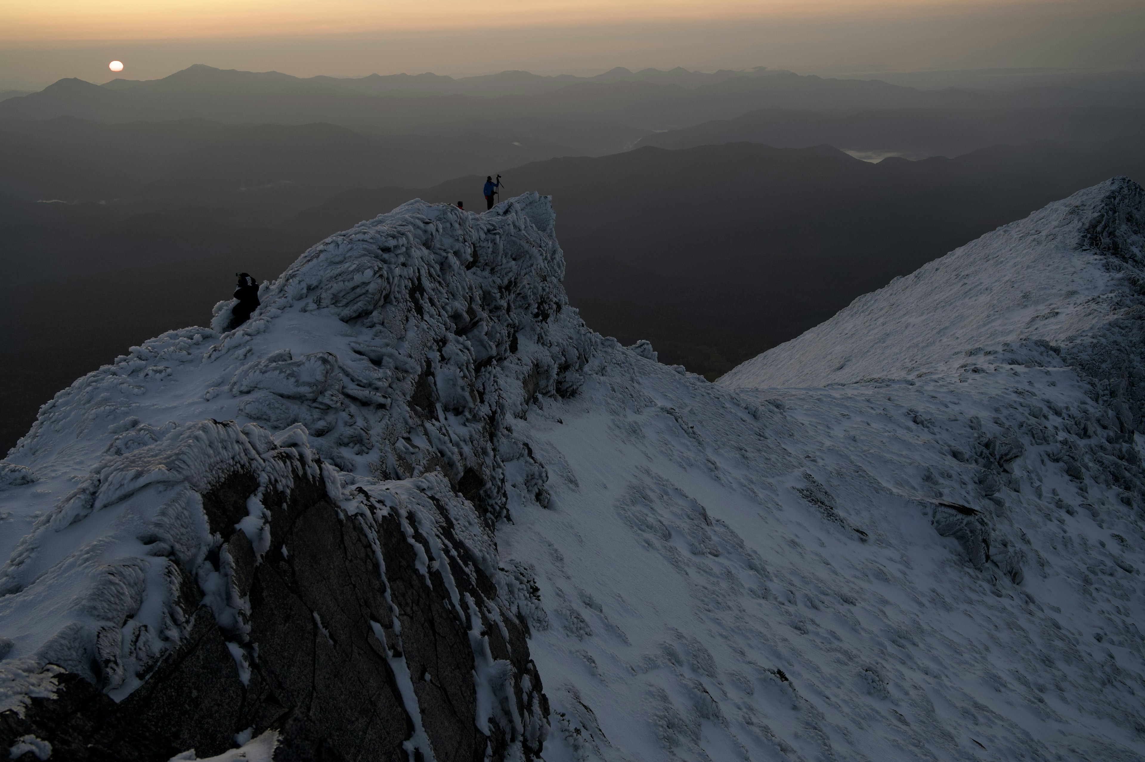 雪に覆われた山の頂上と夕日の景色