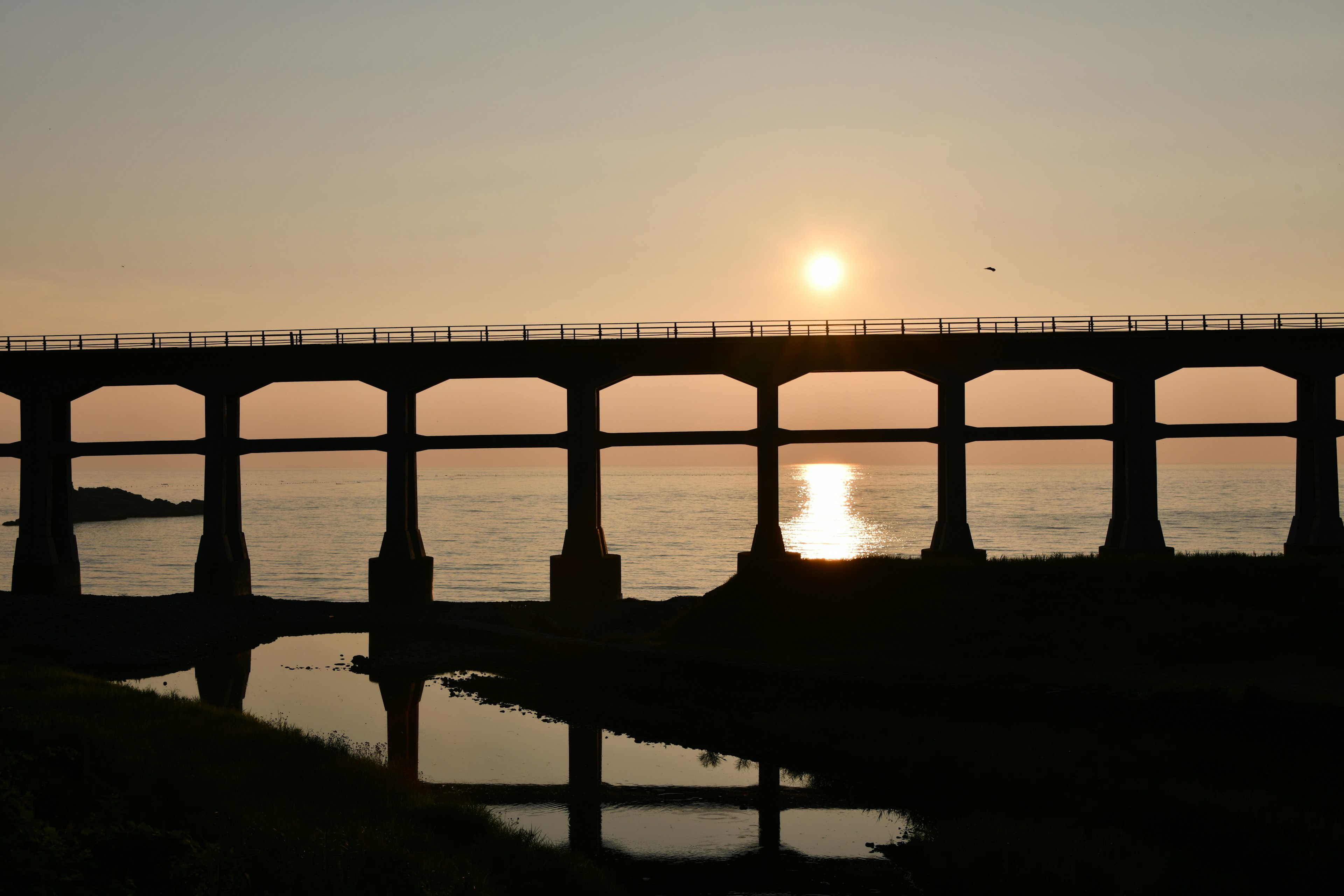 Silhouette einer Brücke über dem Meer mit Sonnenuntergang