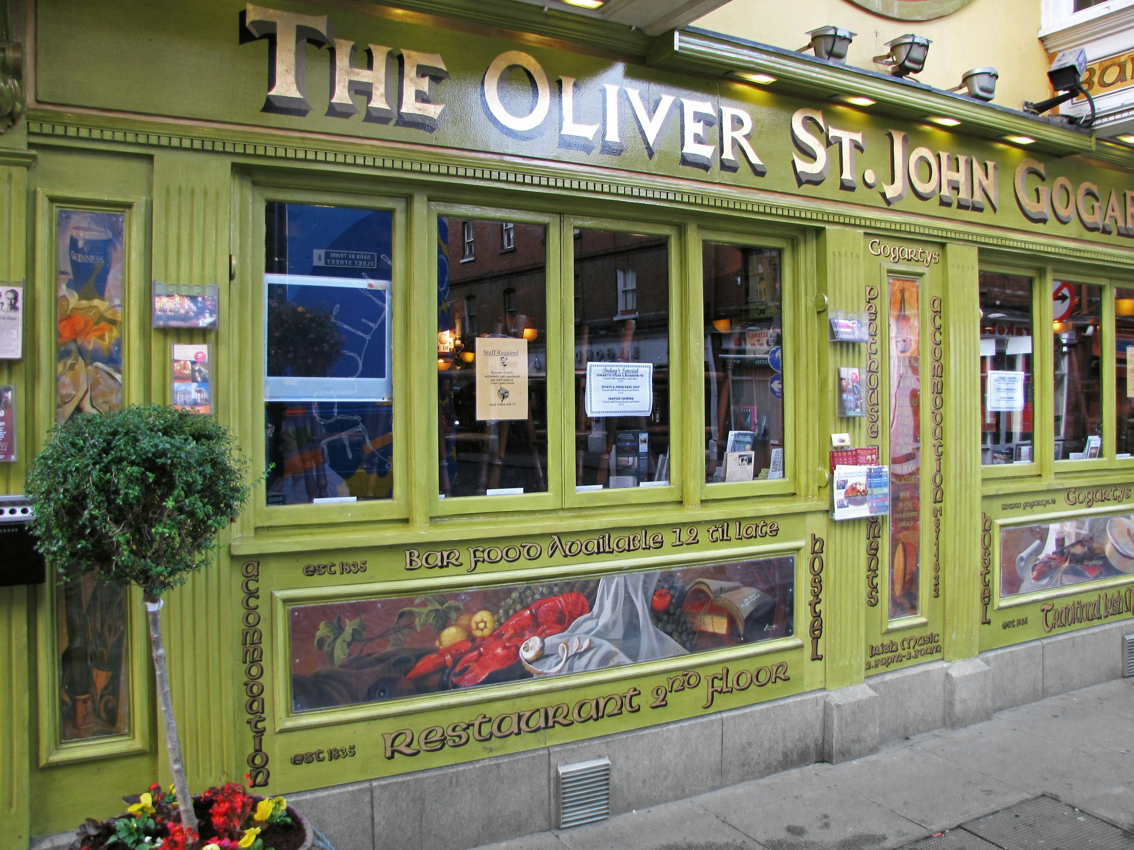 Fasad pub The Oliver St. John Gogarty dengan eksterior hijau dan mural dekoratif