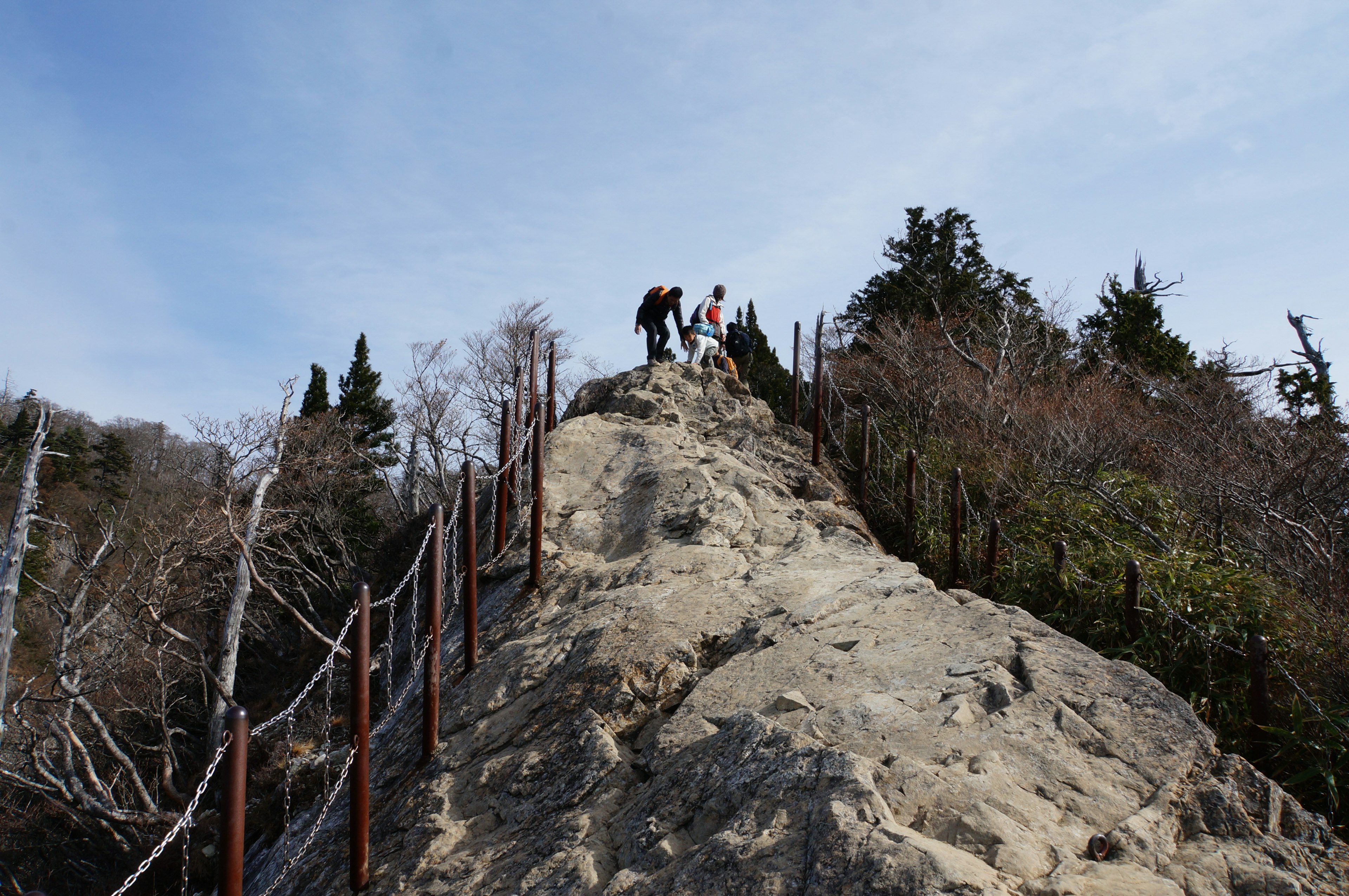 Excursionistas subiendo una montaña rocosa bajo un cielo azul