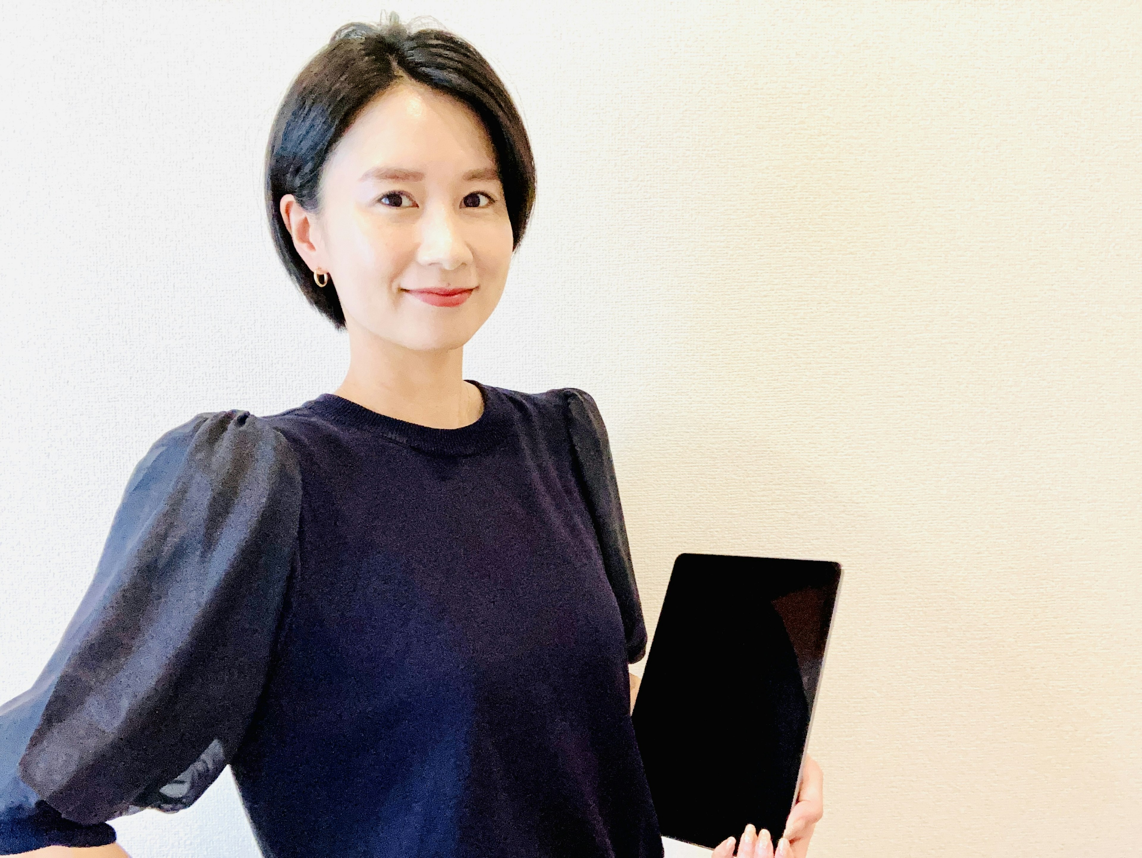 A woman smiling while holding a tablet